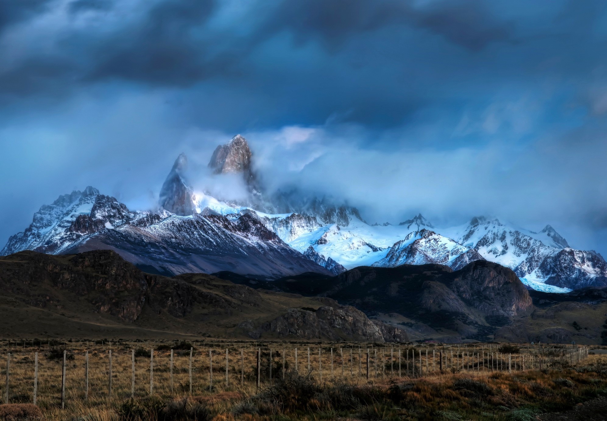 Snow-capped mountains in Argentina under cloudy skies HD Wallpaper