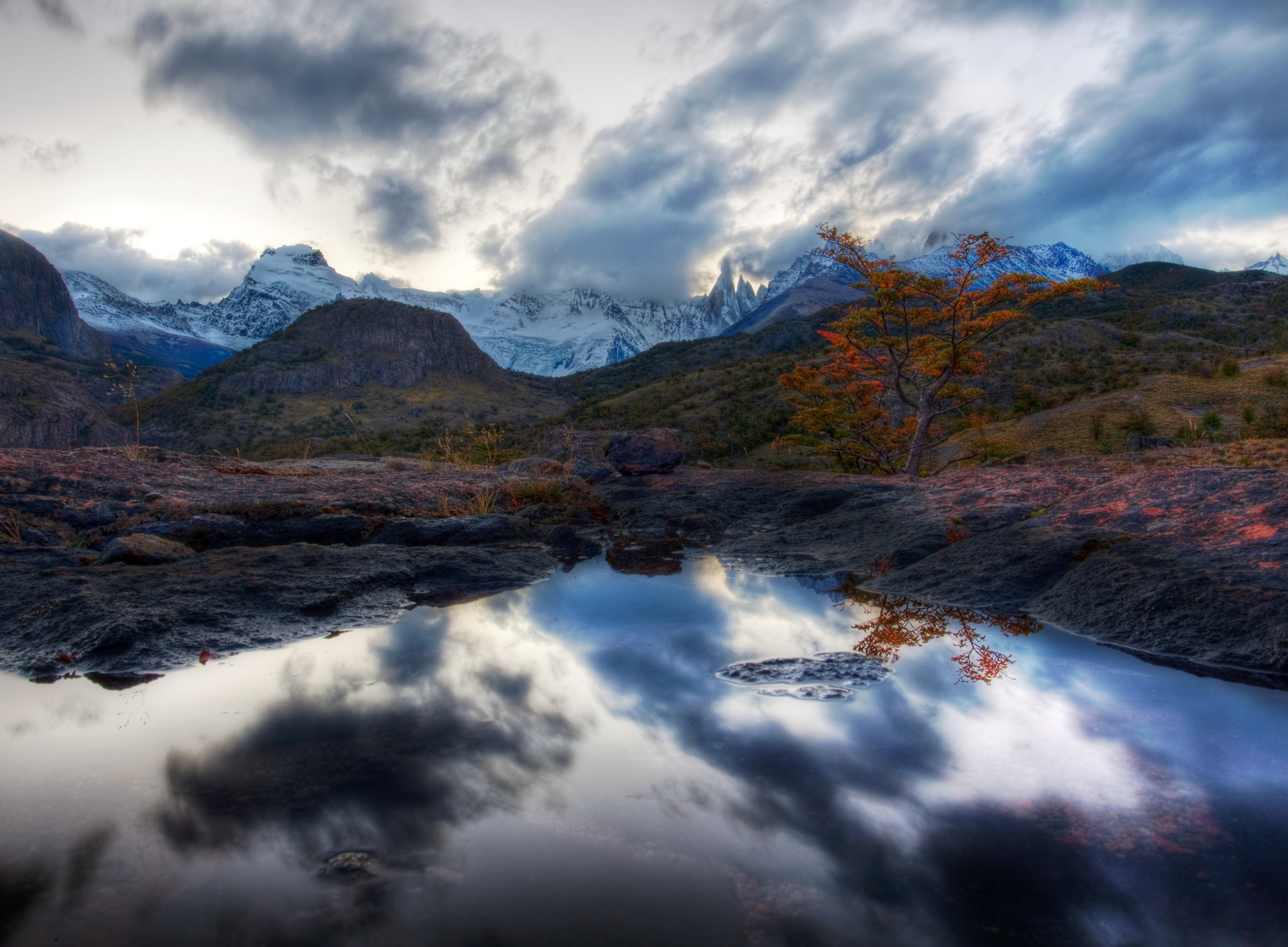 Mountains and clouds reflected in a puddle in Patagonia HD Wallpaper