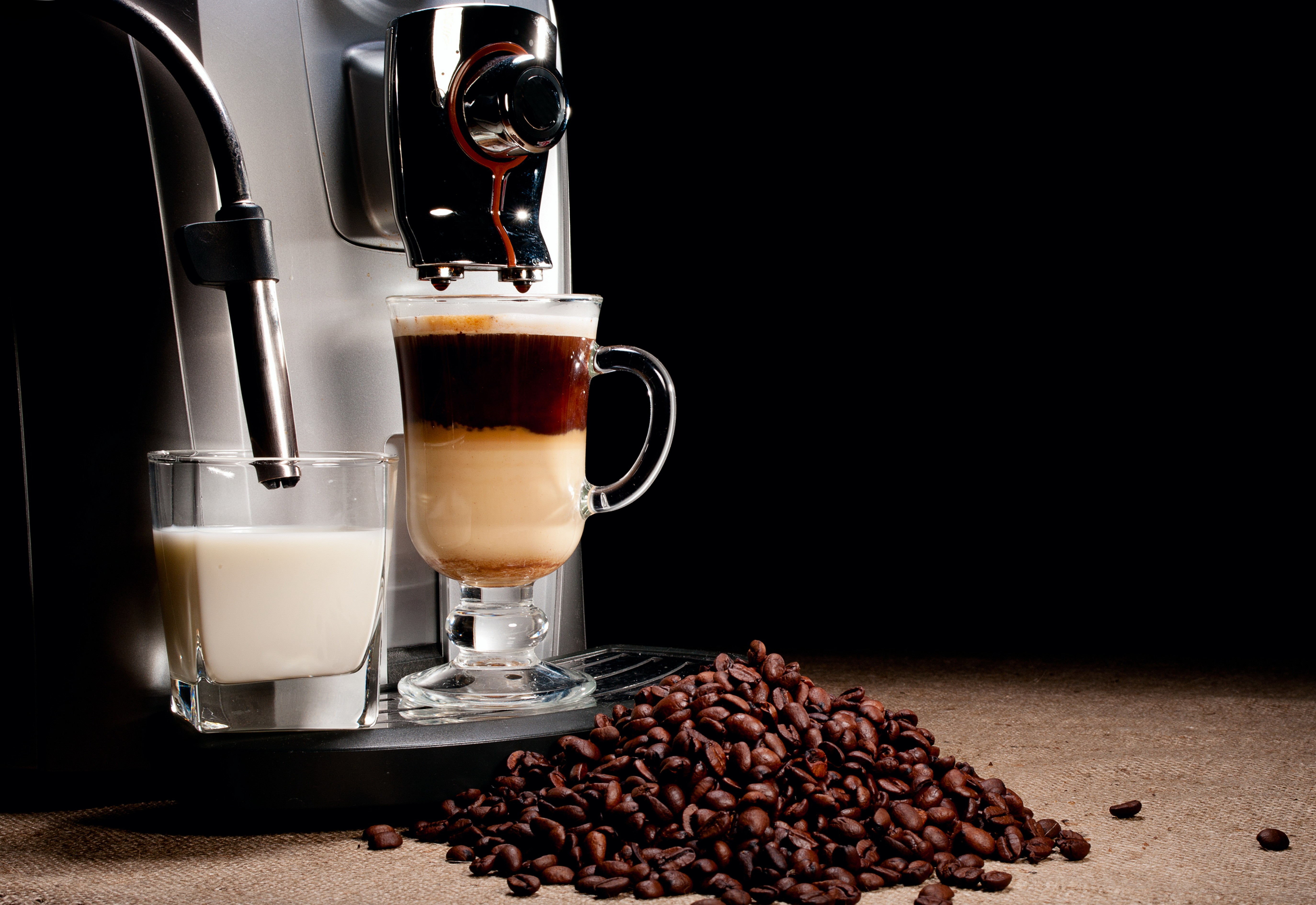 Coffee machine making a layered coffee drink with milk and coffee beans HD Wallpaper