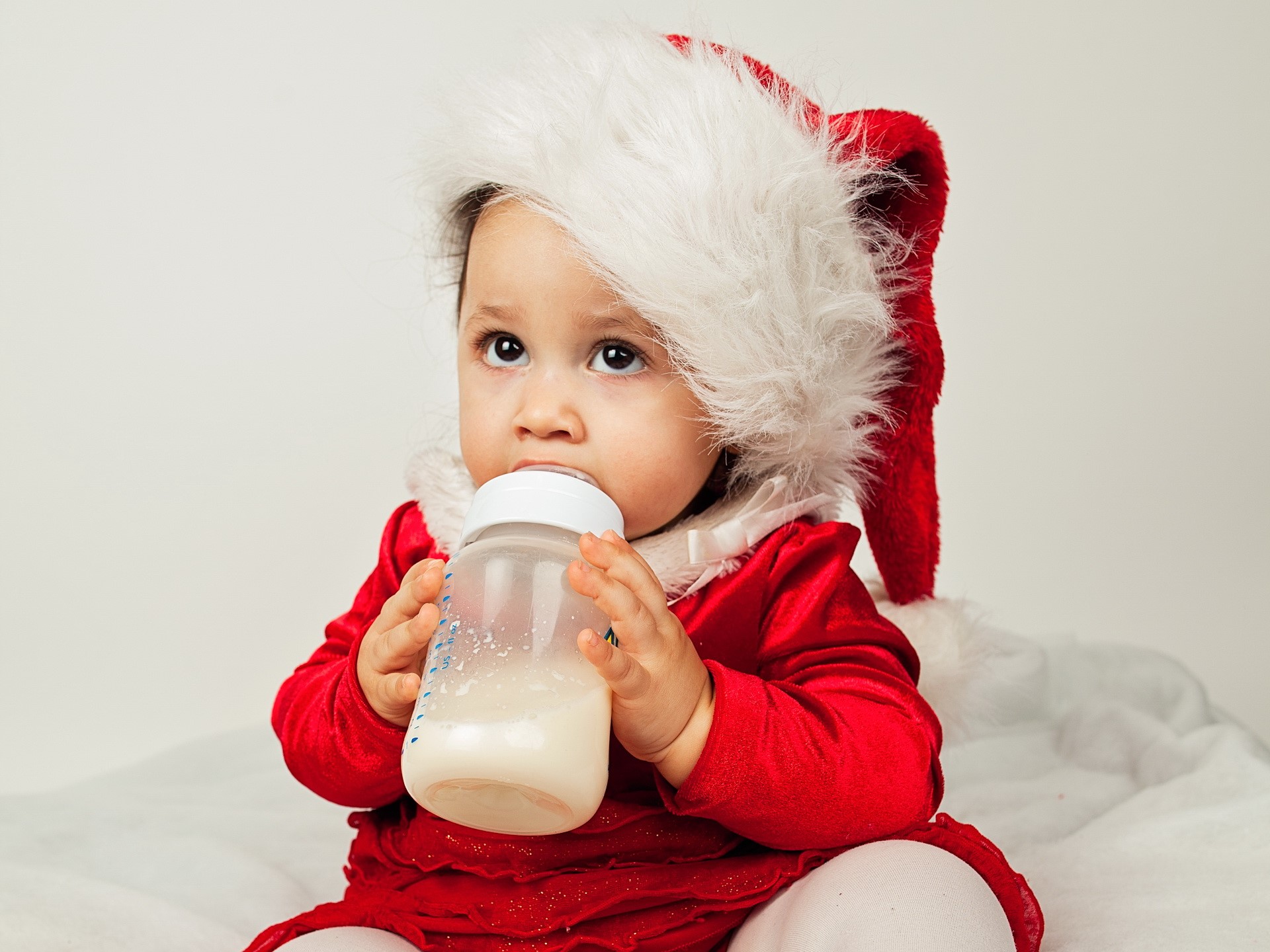 Baby in Santa hat drinking from bottle HD Wallpaper