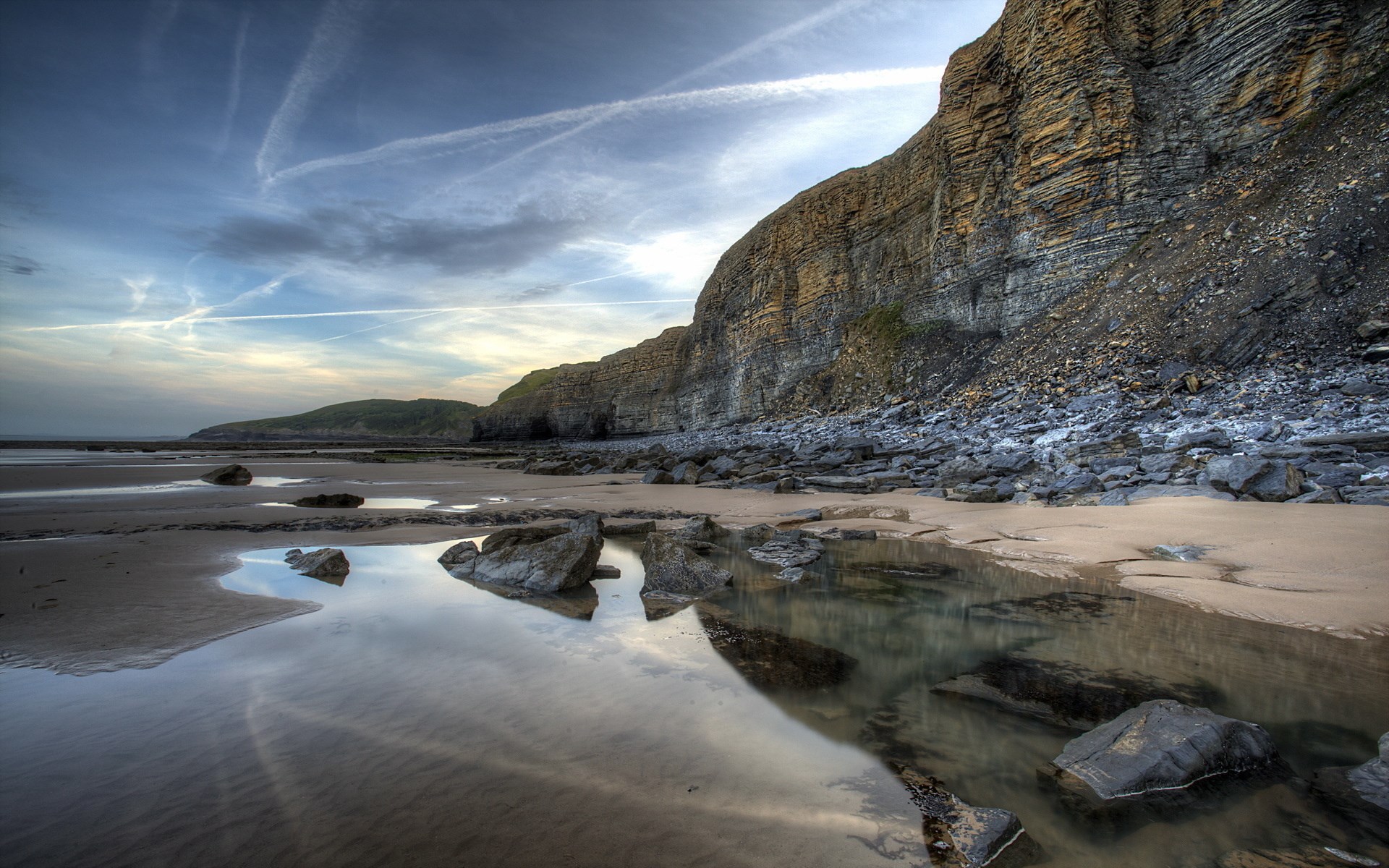 Rocky cliff face overlooking a beach with tide pools HD Wallpaper