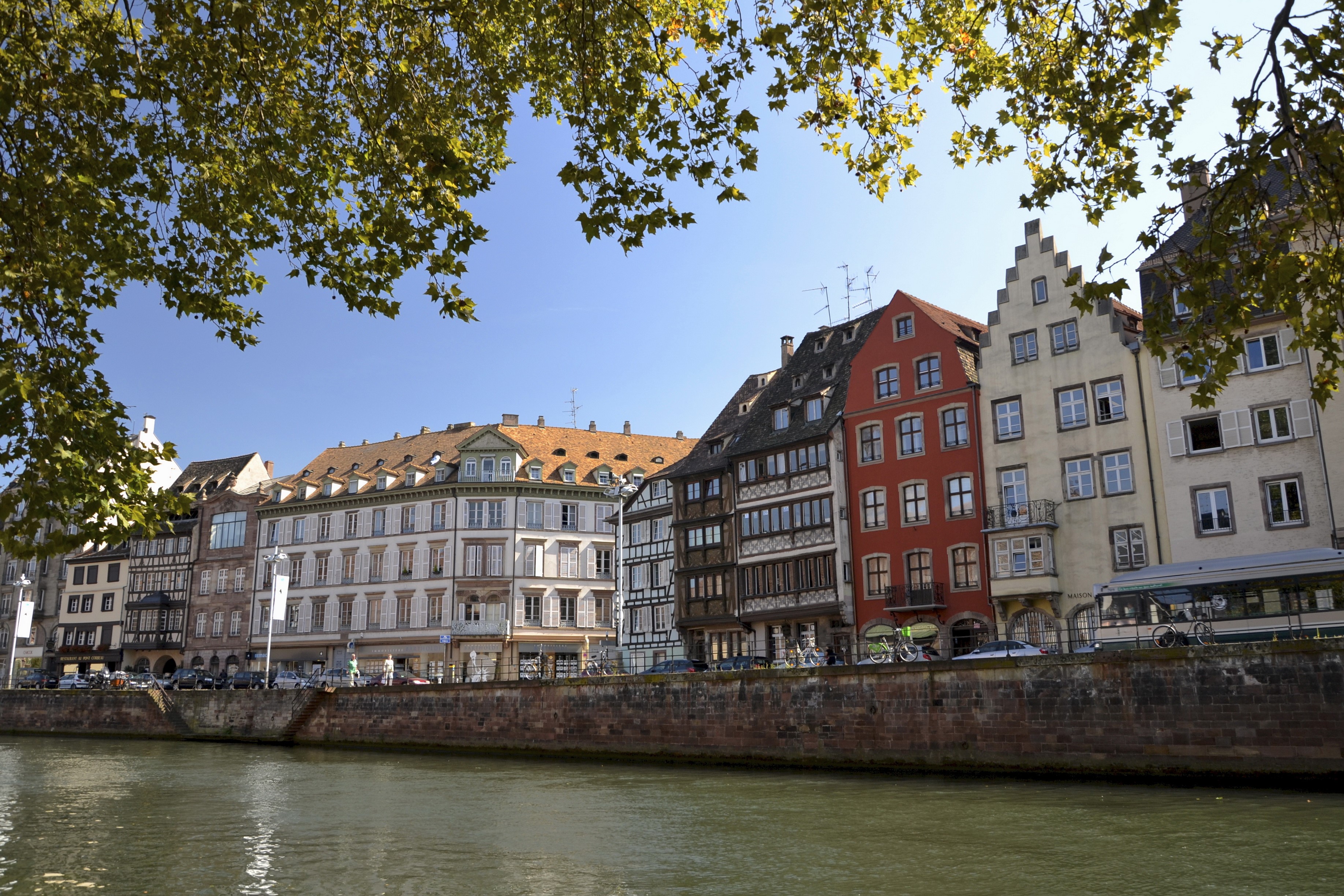 Strasbourg riverfront with historic buildings and trees HD Wallpaper