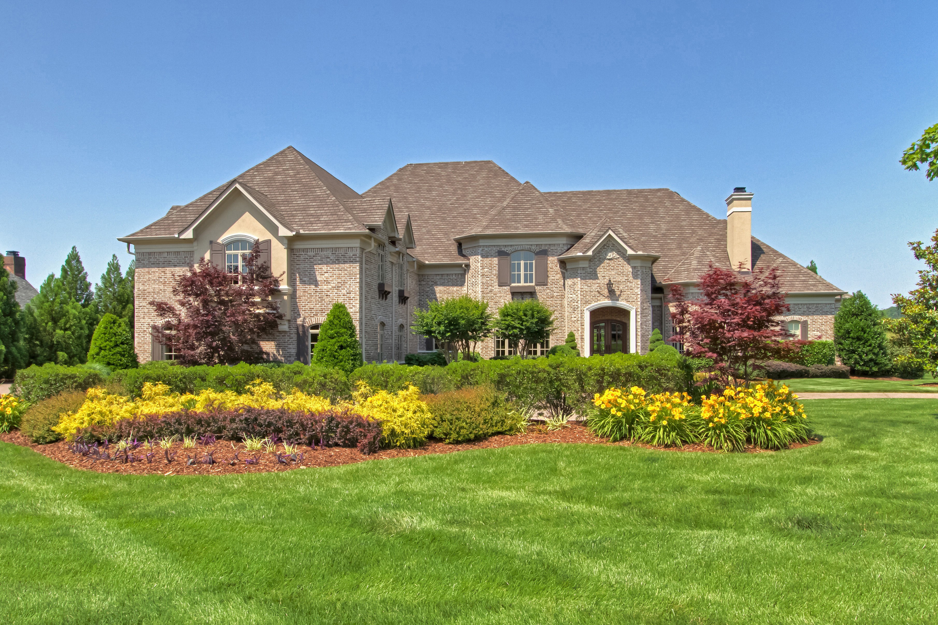 Large brick mansion with manicured gardens and lawn HD Wallpaper