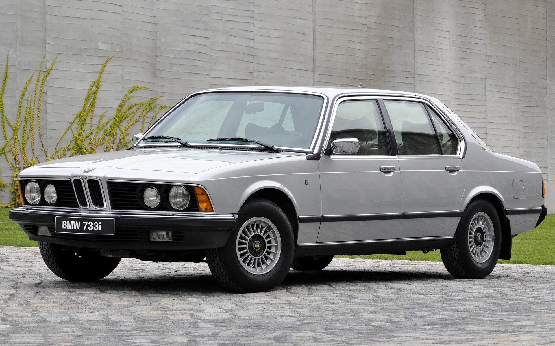 Silver BMW 733i parked on a stone driveway HD Wallpaper