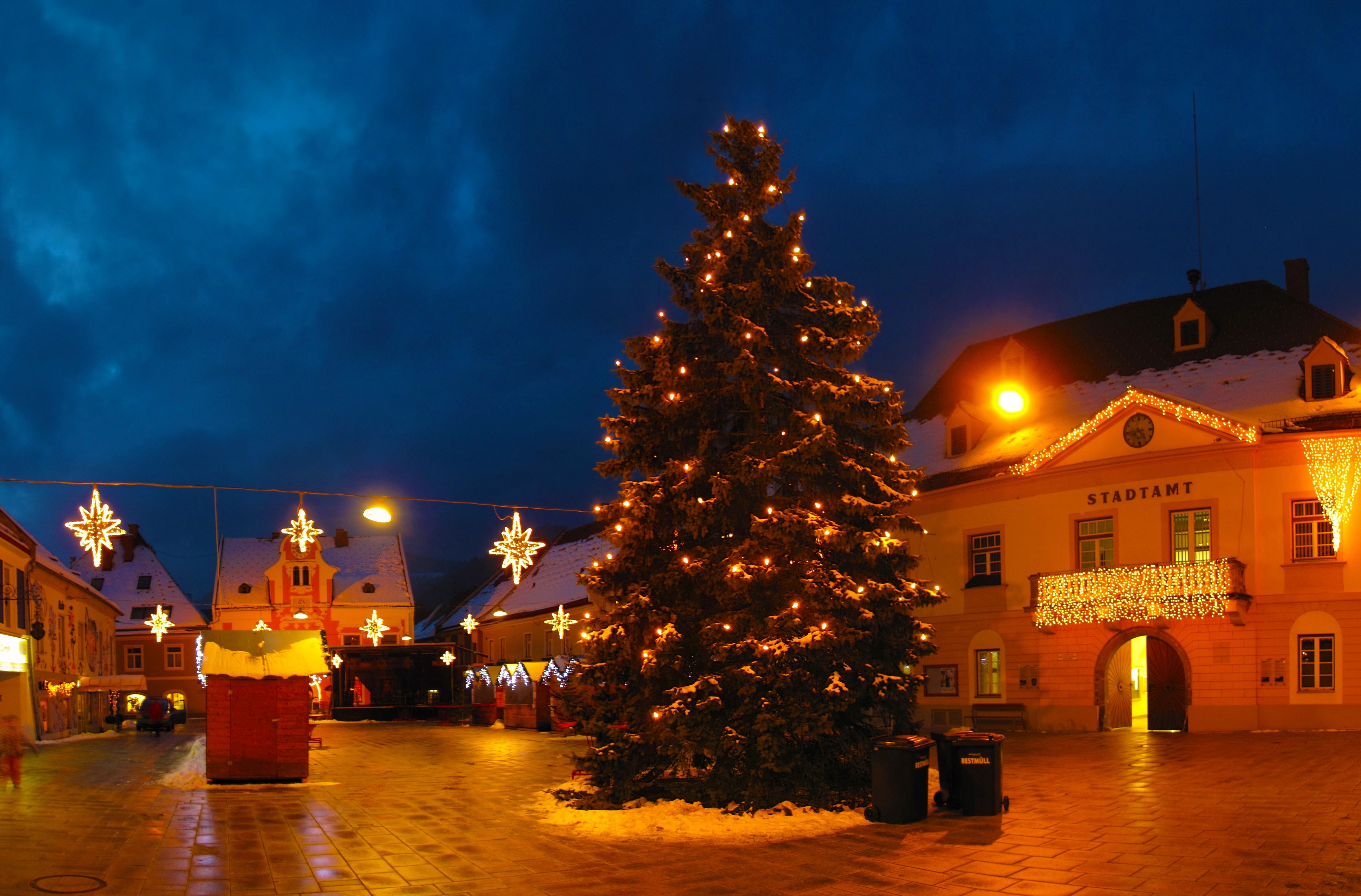 Christmas tree and decorations in a town square at night HD Wallpaper