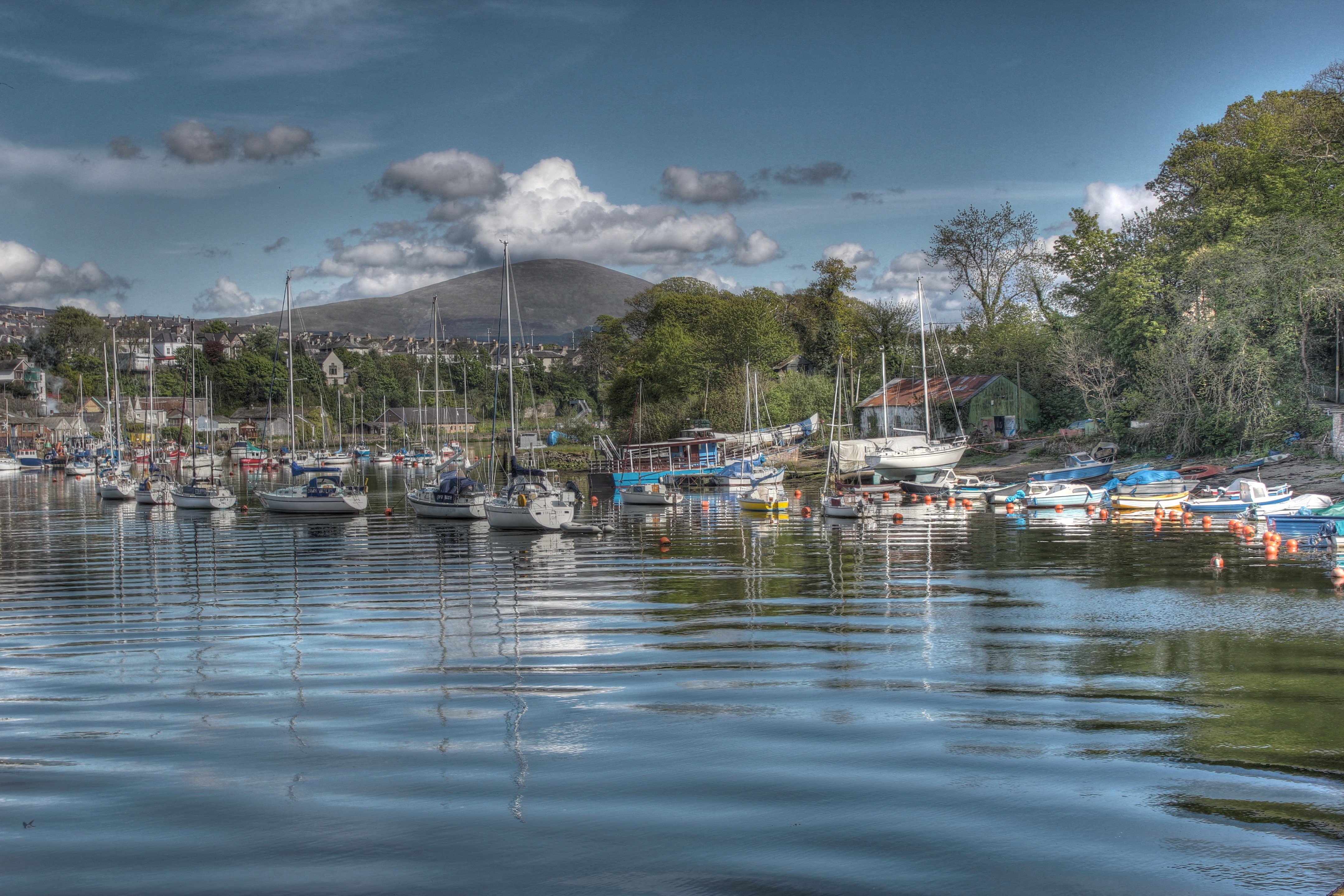 Boats docked in a harbor with mountains and houses in the background HD Wallpaper