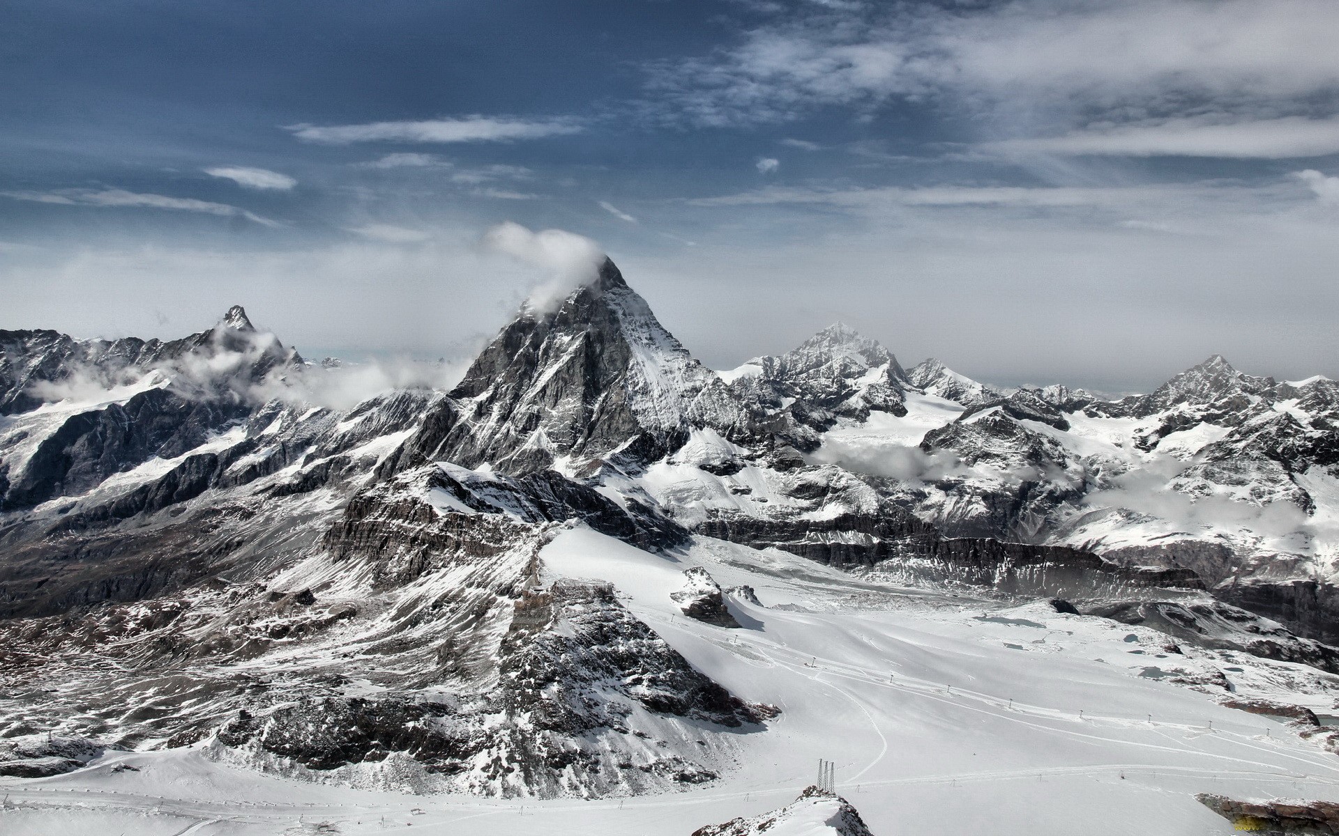Snow-covered mountains under a cloudy sky HD Wallpaper