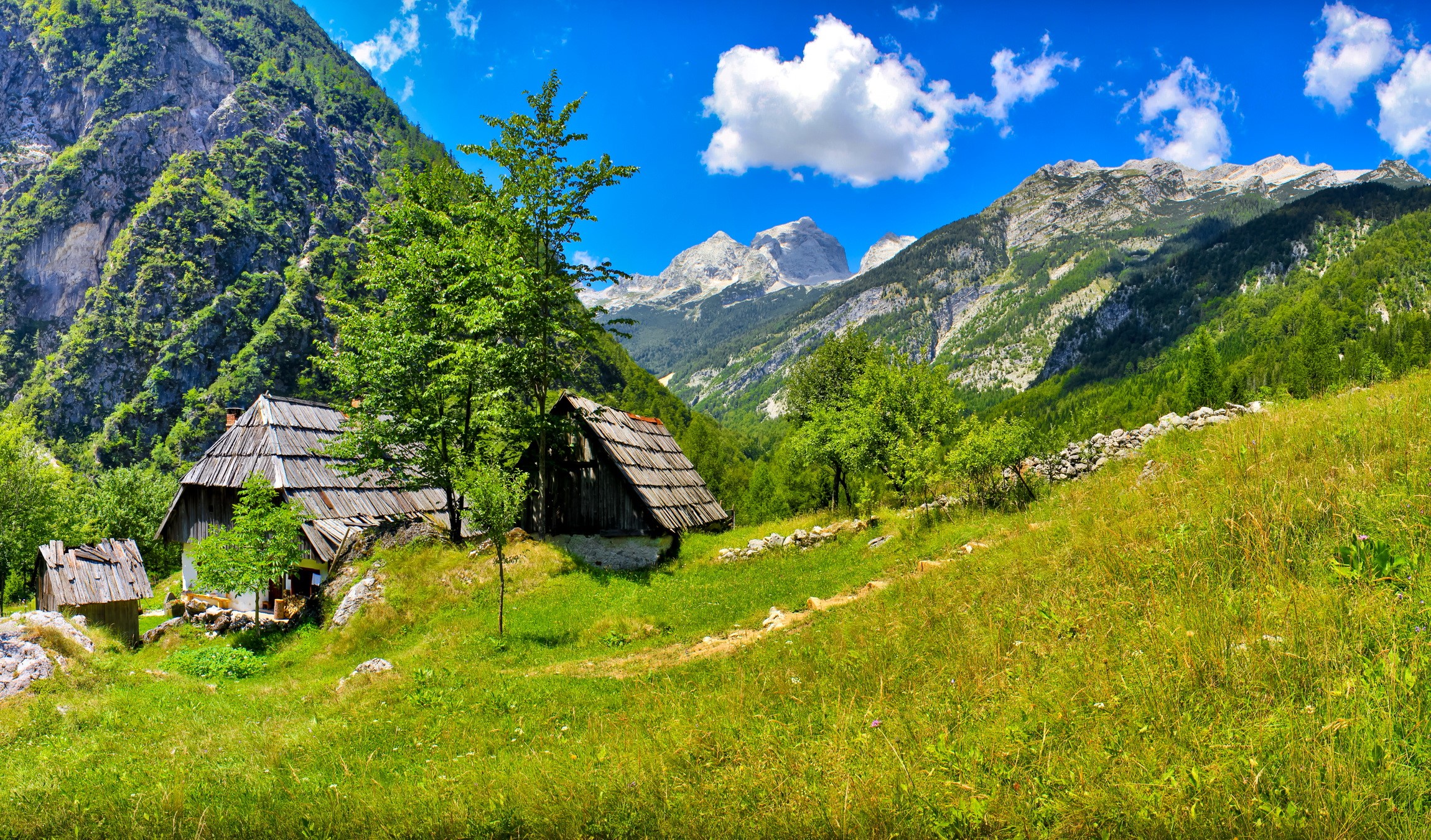 Wooden huts in a green mountain valley in Slovenia HD Wallpaper