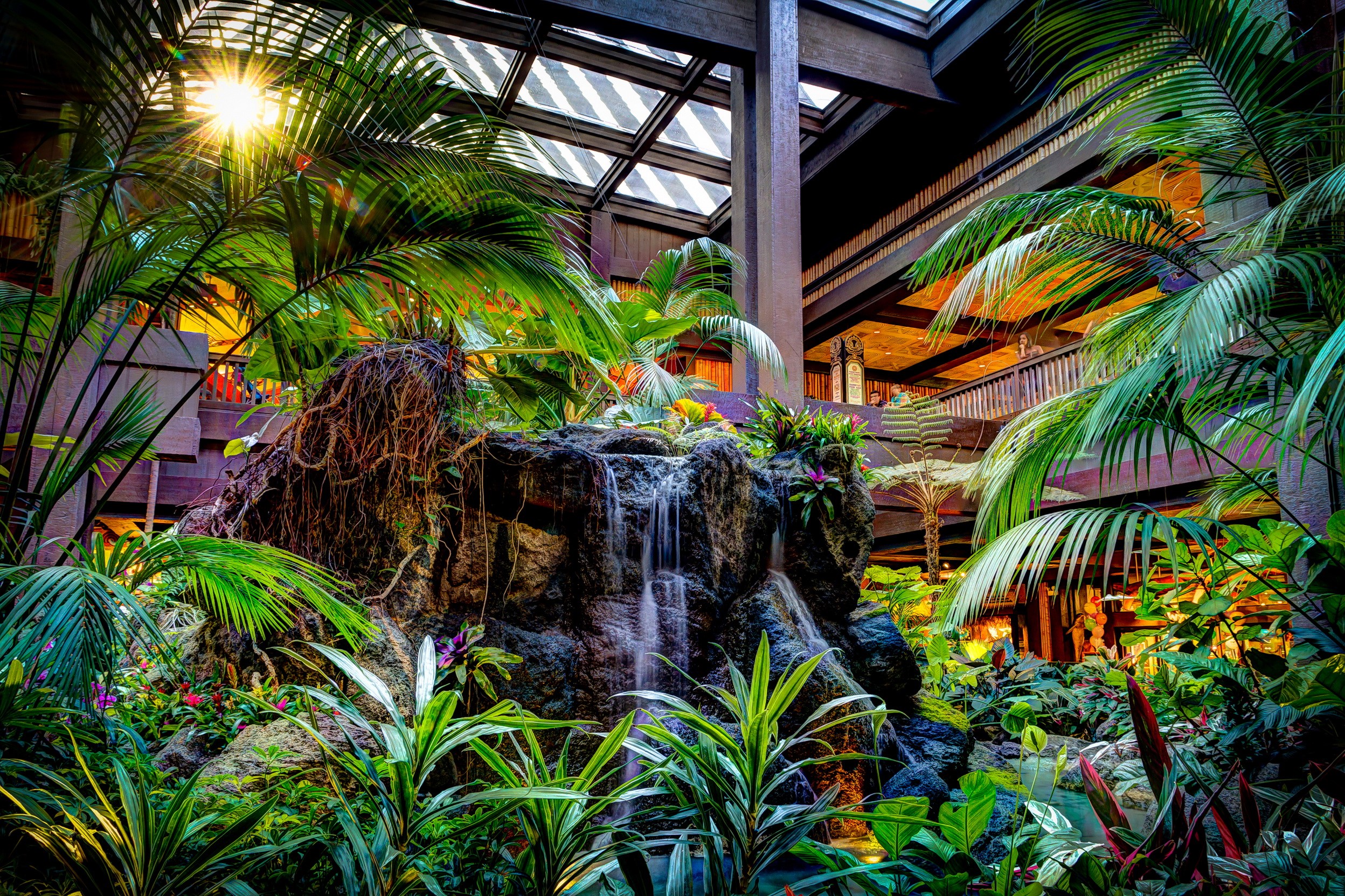 Indoor tropical waterfall with palm trees and sunlight HD Wallpaper