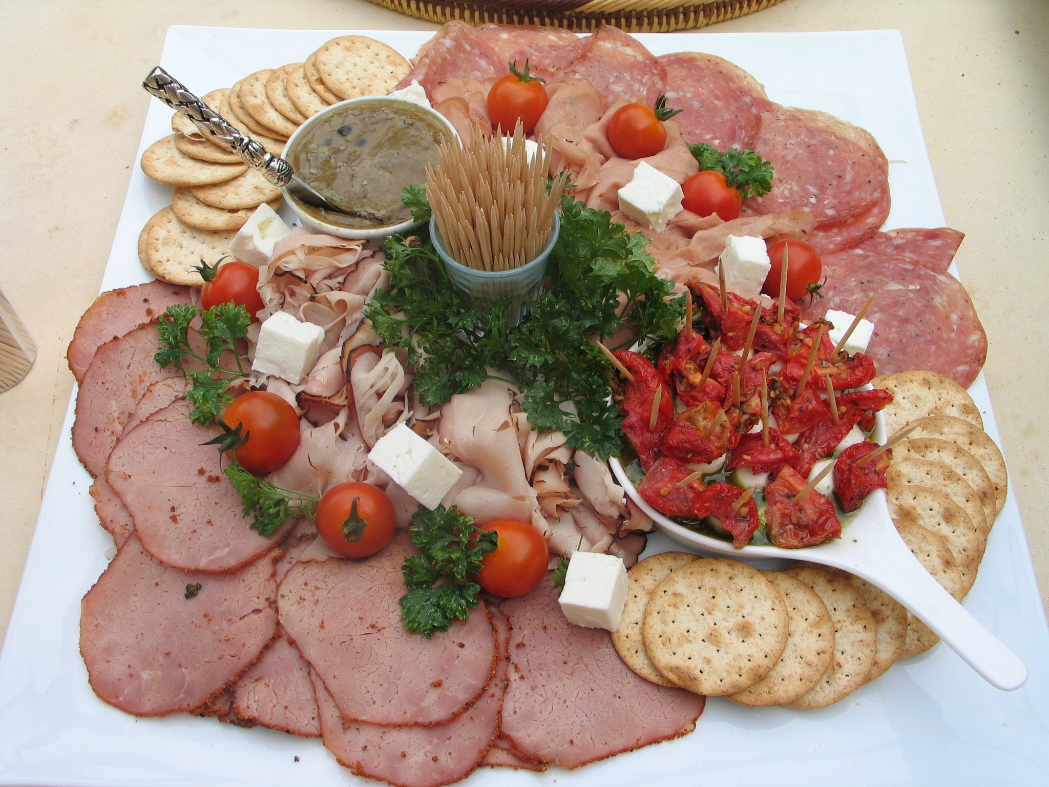 Charcuterie board with meats, cheese, crackers, and tomatoes HD Wallpaper