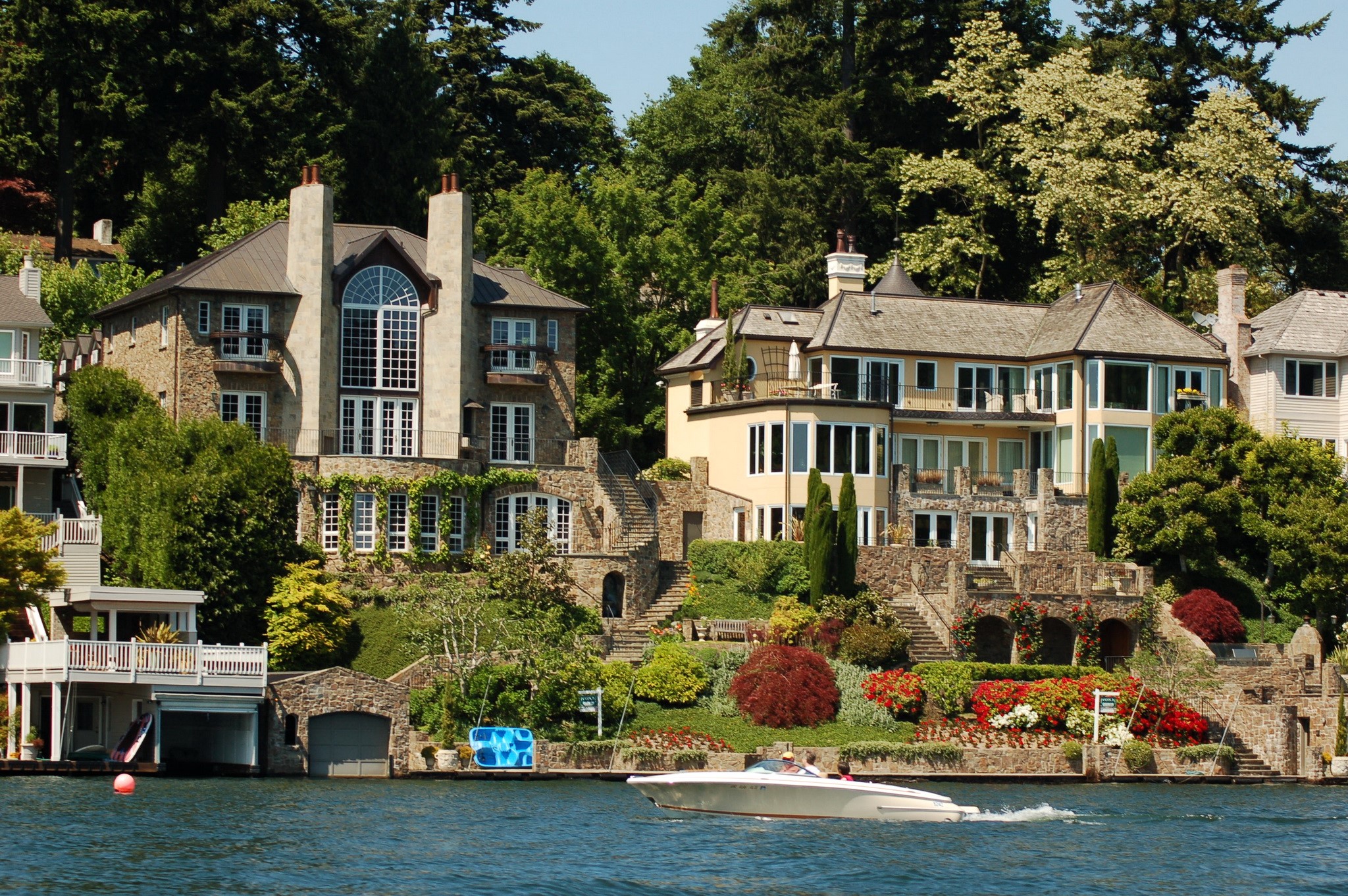 Luxury houses on a hillside overlooking a body of water with a boat HD Wallpaper