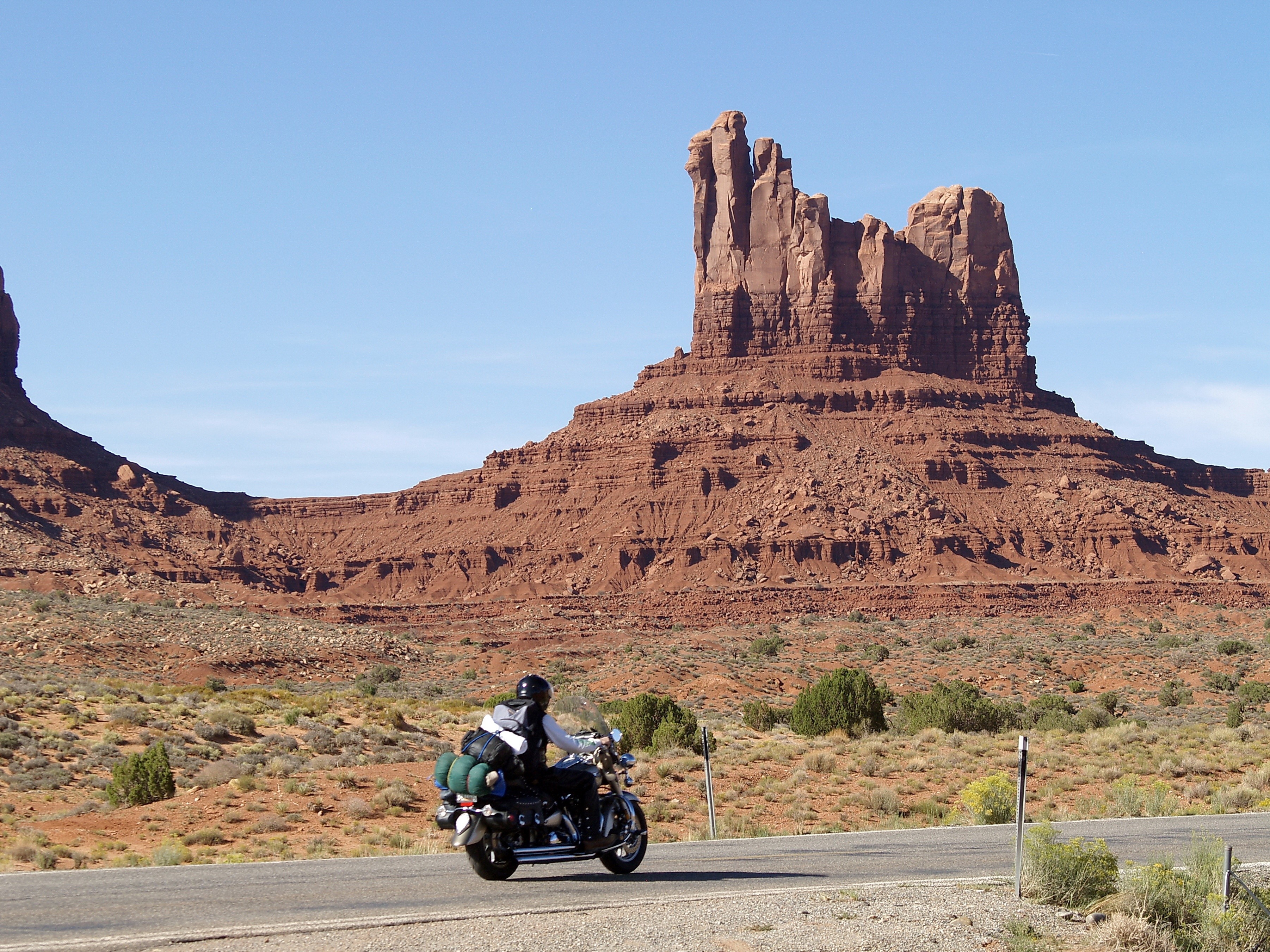 Motorcyclist riding on a road in Monument Valley HD Wallpaper