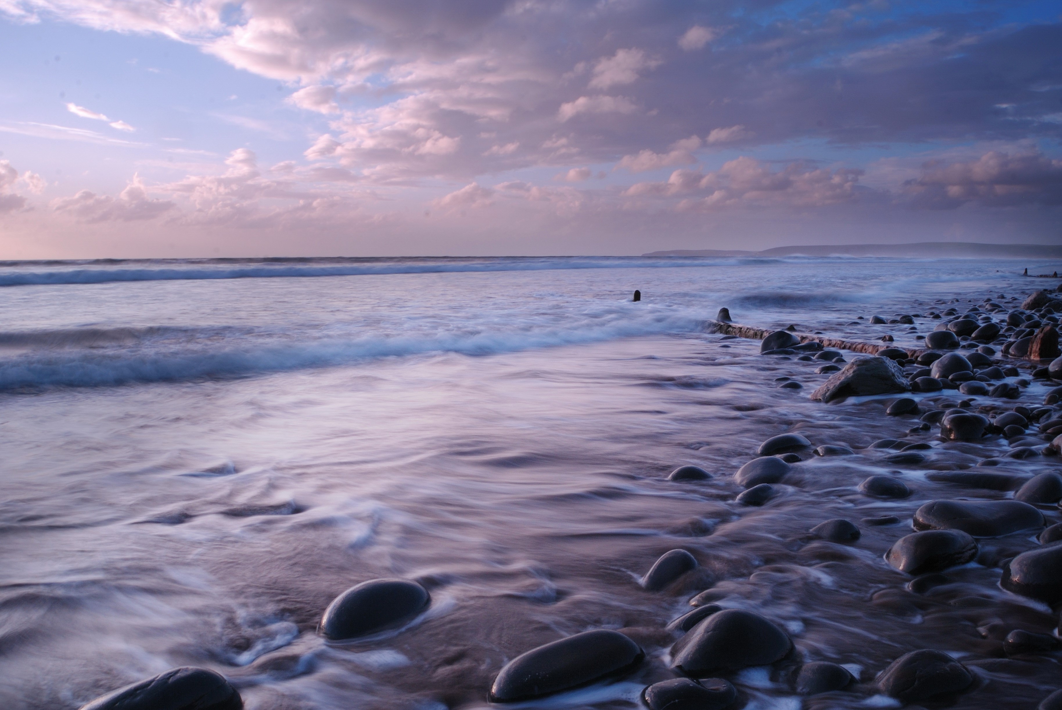 Ocean waves crashing on a rocky beach at sunset HD Wallpaper