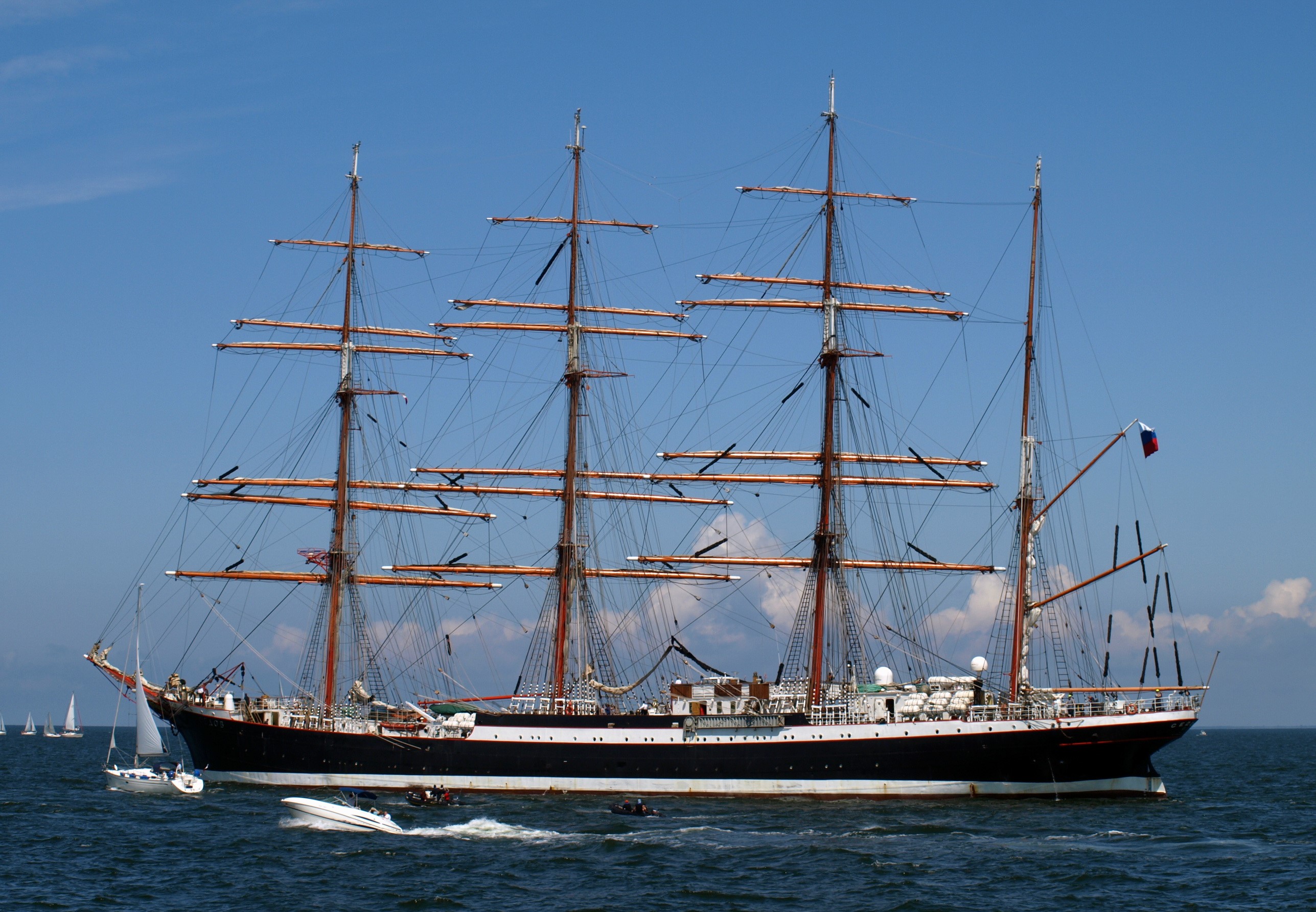 Tall ship sailing on the ocean with smaller boats HD Wallpaper