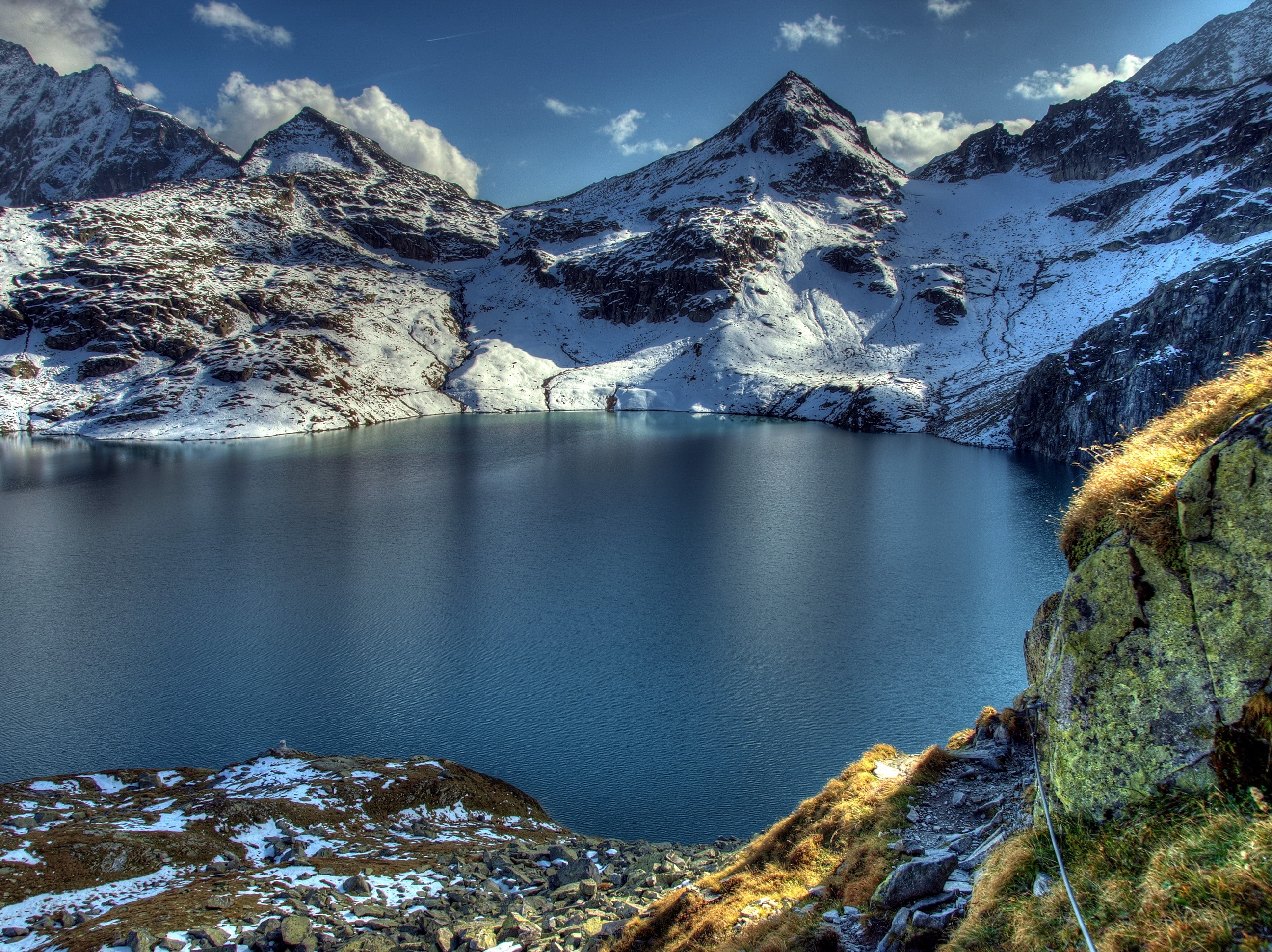 Snow-capped mountains surround a deep blue lake in the Alps HD Wallpaper