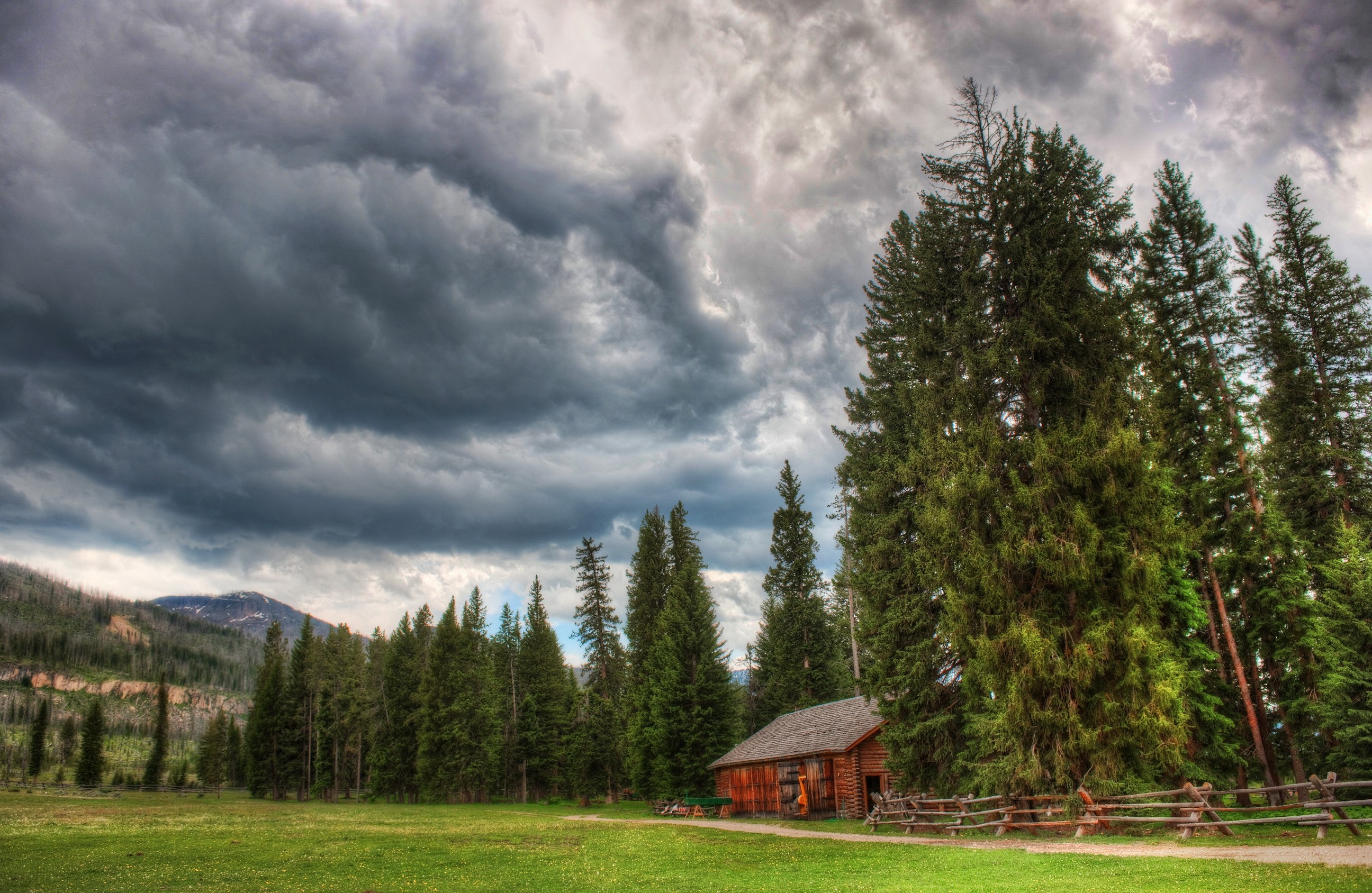 Wooden cabin in a forest with stormy skies HD Wallpaper
