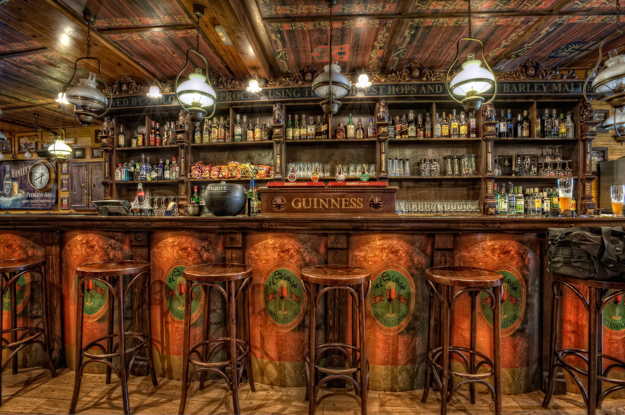 Interior of a traditional Irish pub with a wooden bar and stools HD Wallpaper