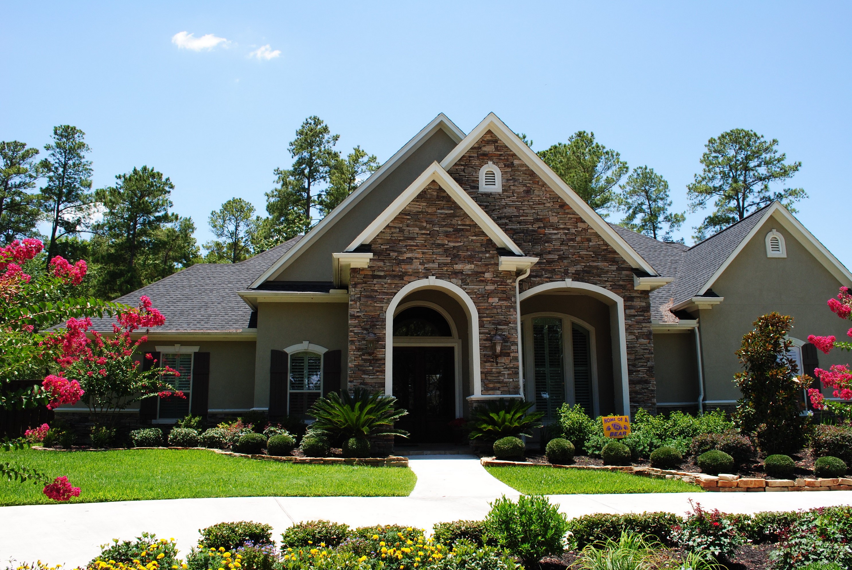 Luxury house with stone facade and manicured landscaping HD Wallpaper