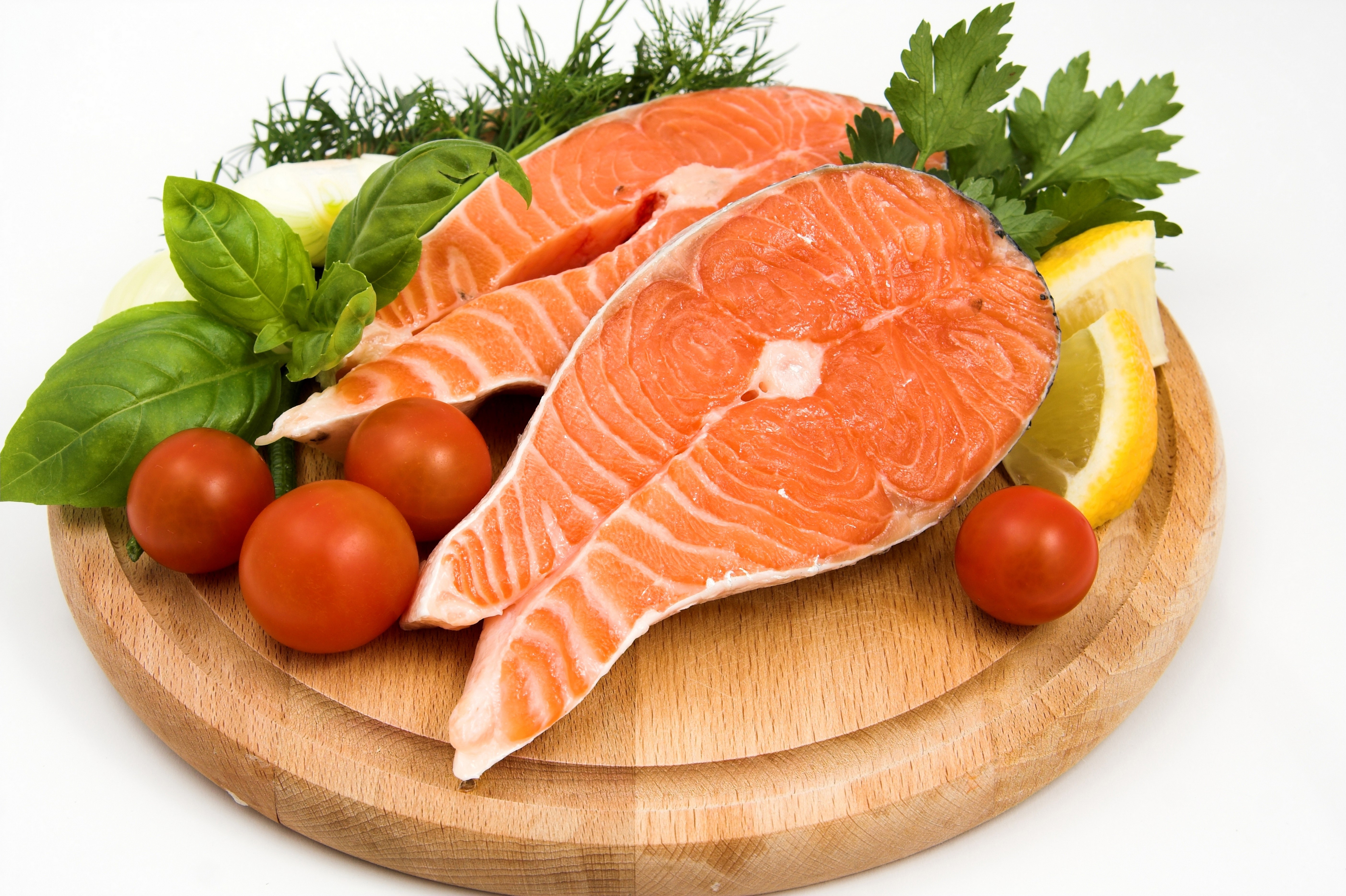 Salmon steaks with tomatoes and herbs on a wooden board HD Wallpaper