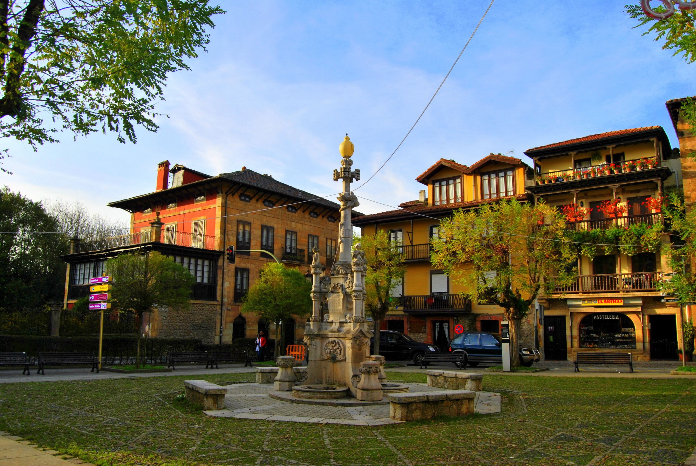Monument in a town square with buildings and trees HD Wallpaper