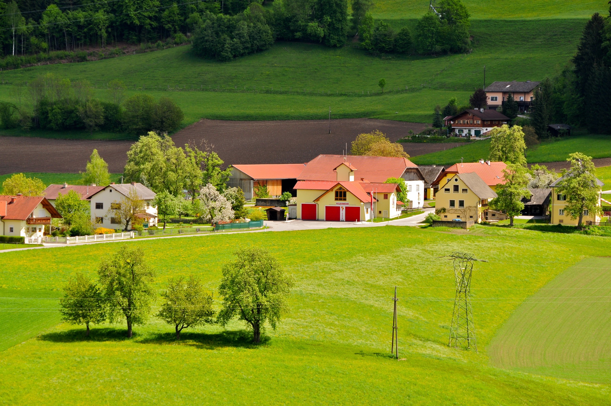 Austrian village with red-roofed houses and green hills HD Wallpaper