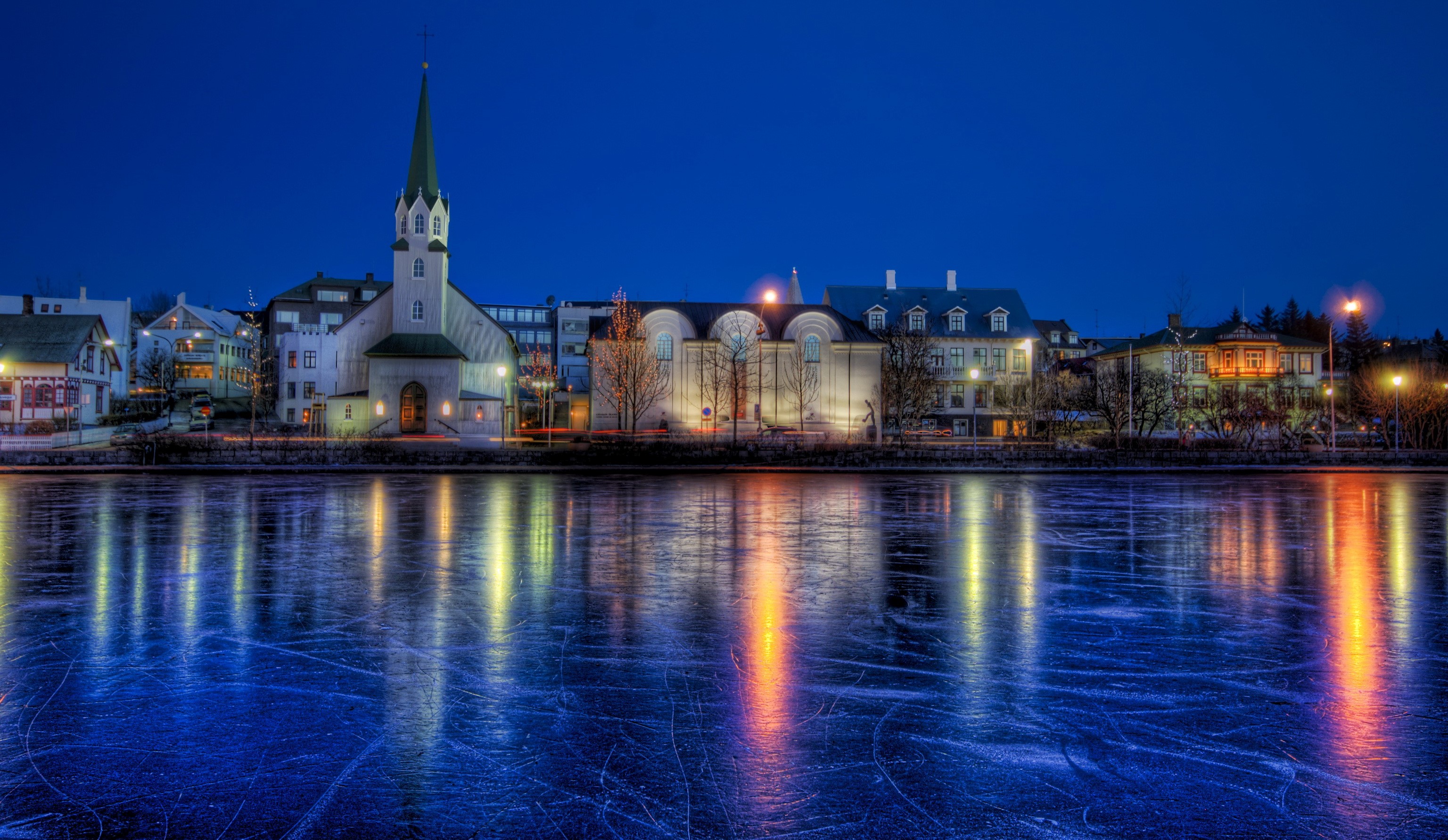 Cityscape with church reflected in frozen lake at night HD Wallpaper