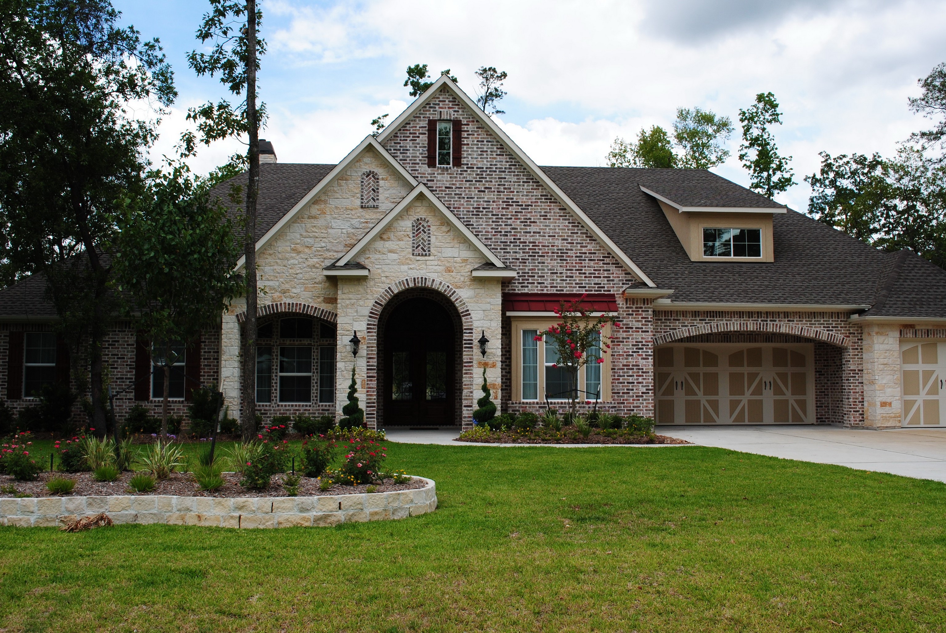 Brick and stone house with manicured lawn and trees HD Wallpaper