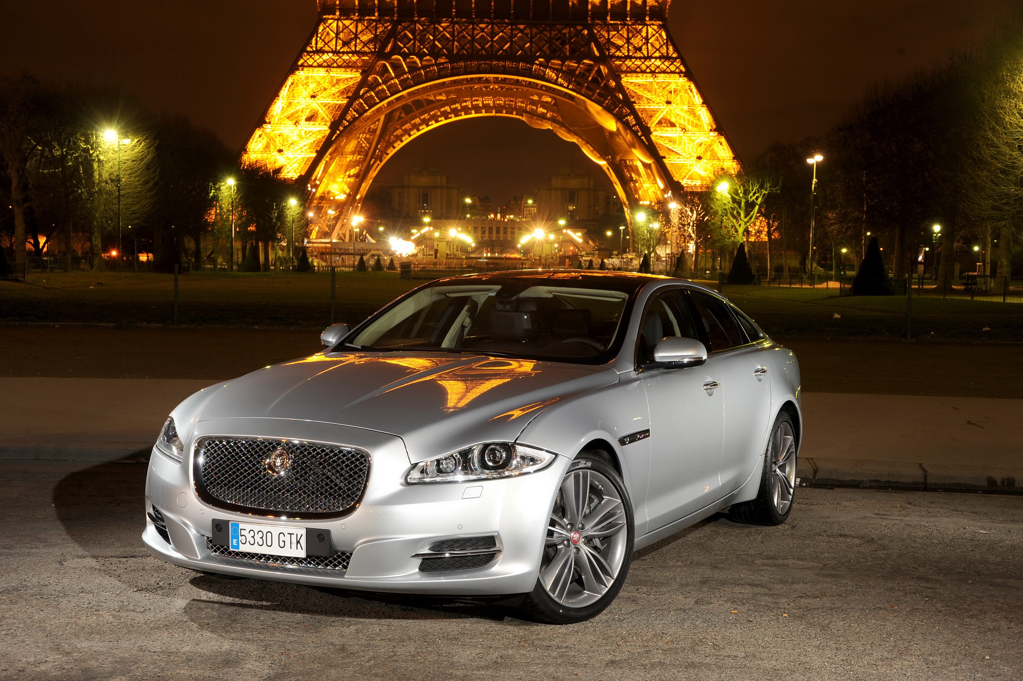 Silver Jaguar XJ in front of the Eiffel Tower at night HD Wallpaper