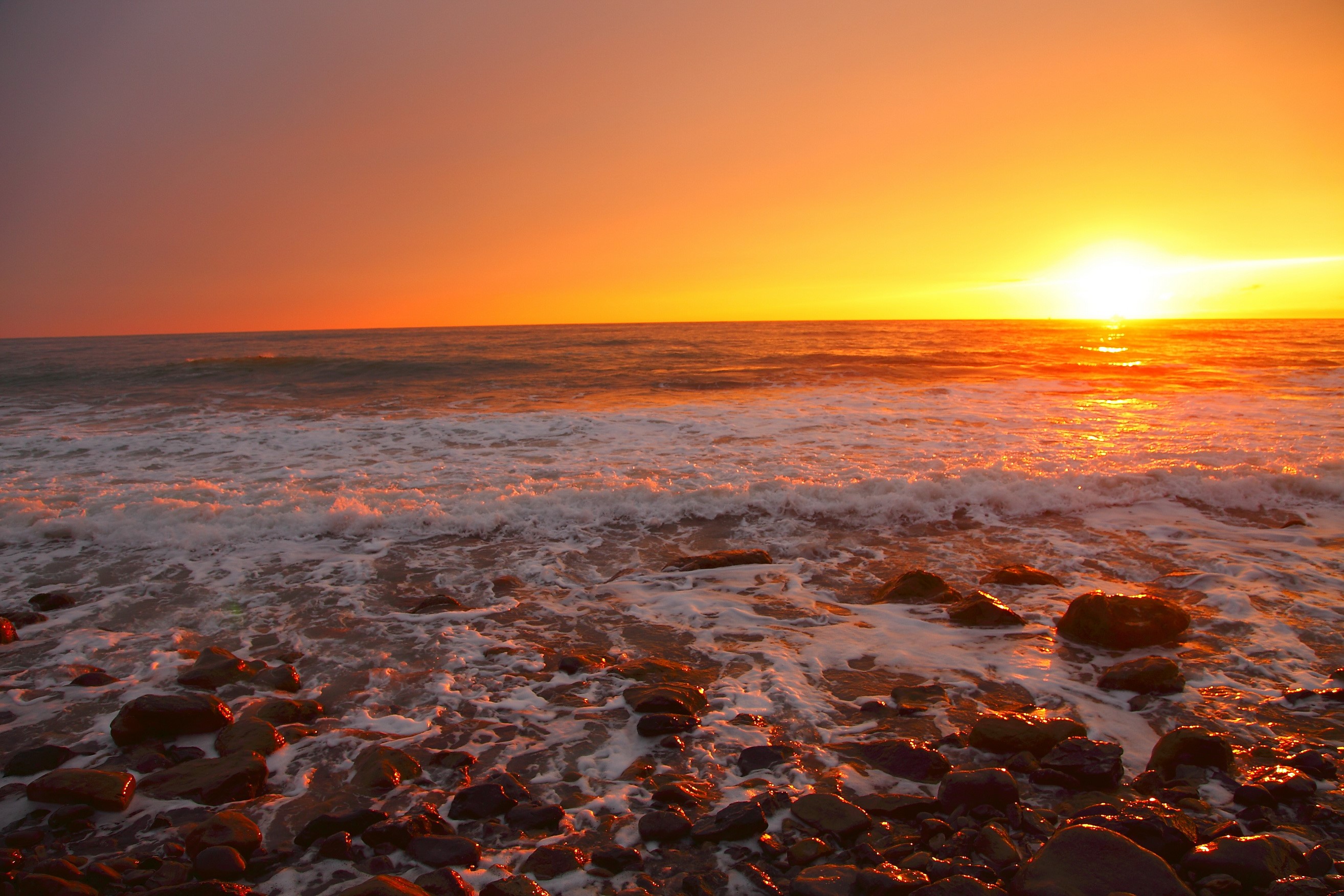 Sunset over the ocean with waves and rocks HD Wallpaper