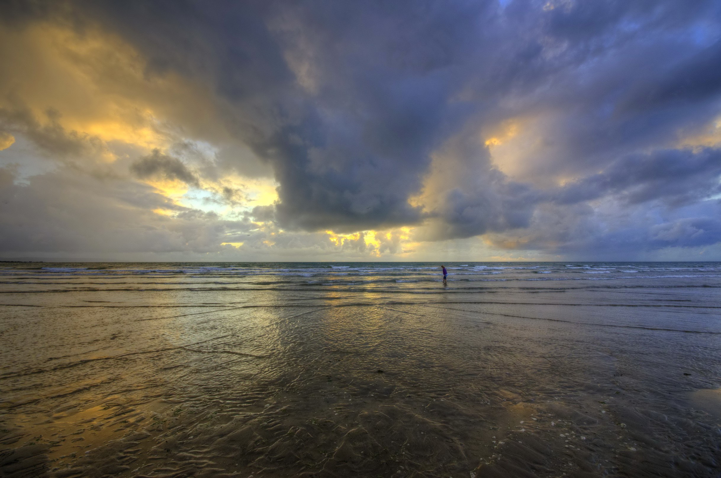 Person standing in the sea under dramatic clouds HD Wallpaper
