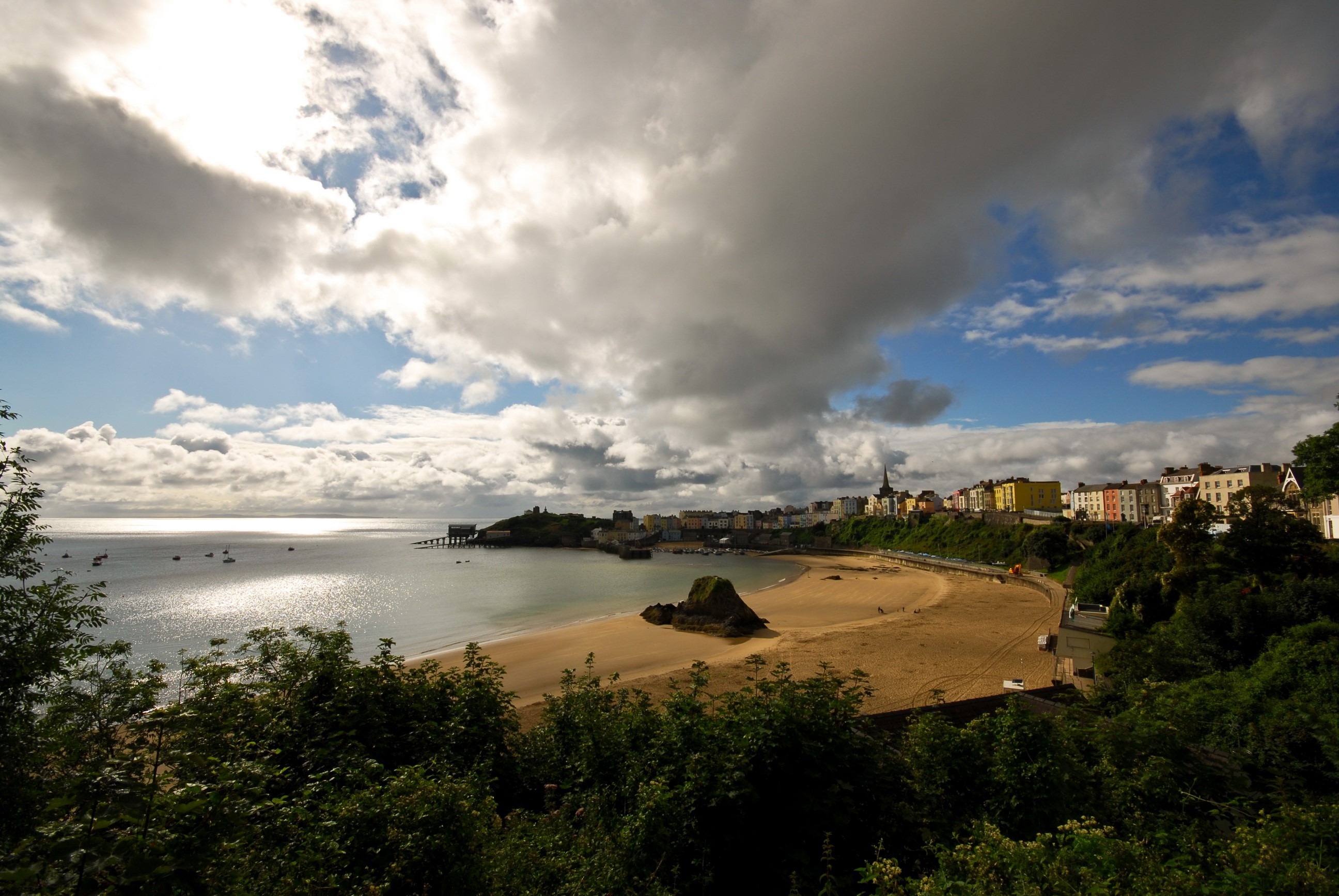 Coastal town with beach and bay under cloudy sky HD Wallpaper