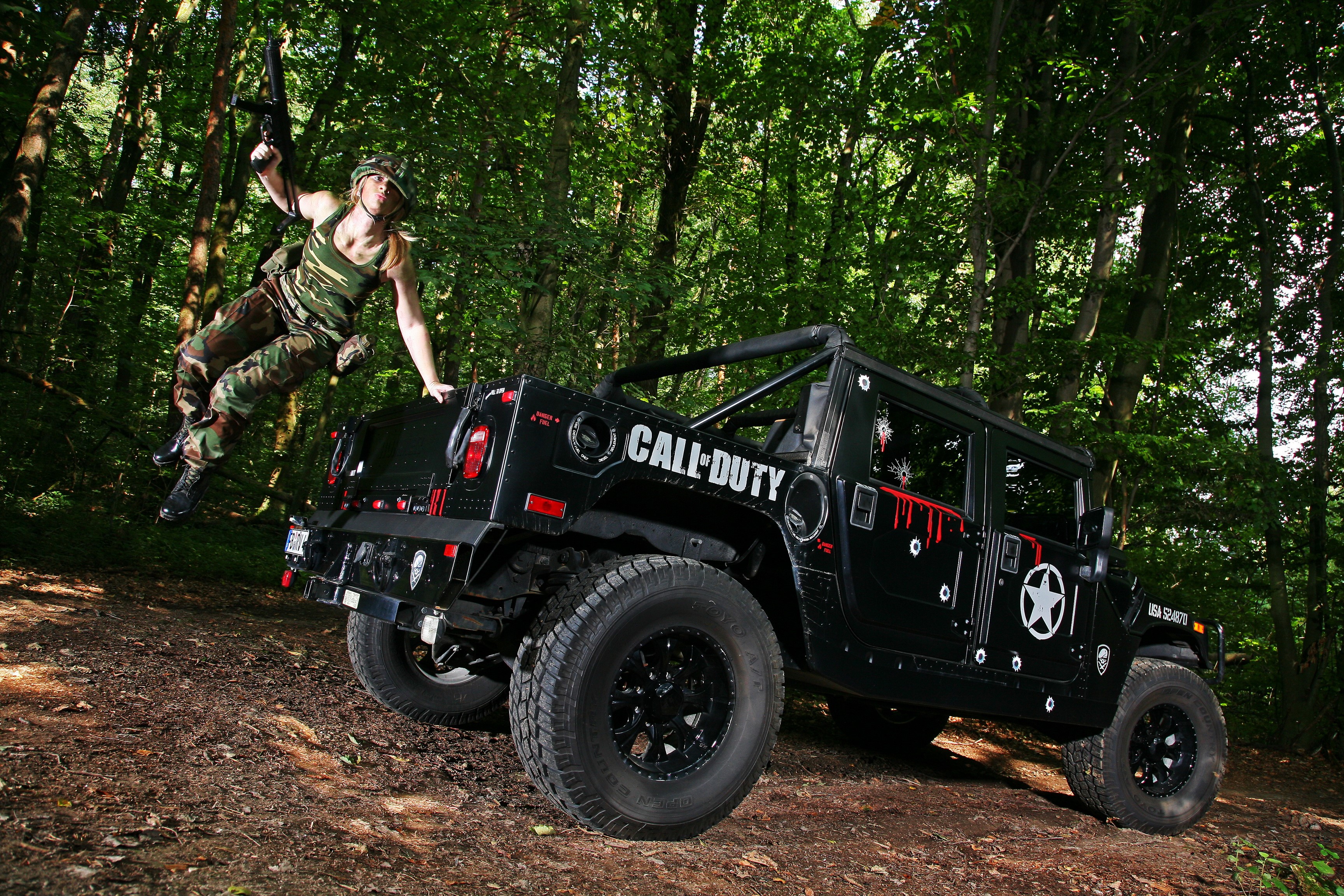 Woman in camouflage jumping from a Call of Duty Hummer HD Wallpaper