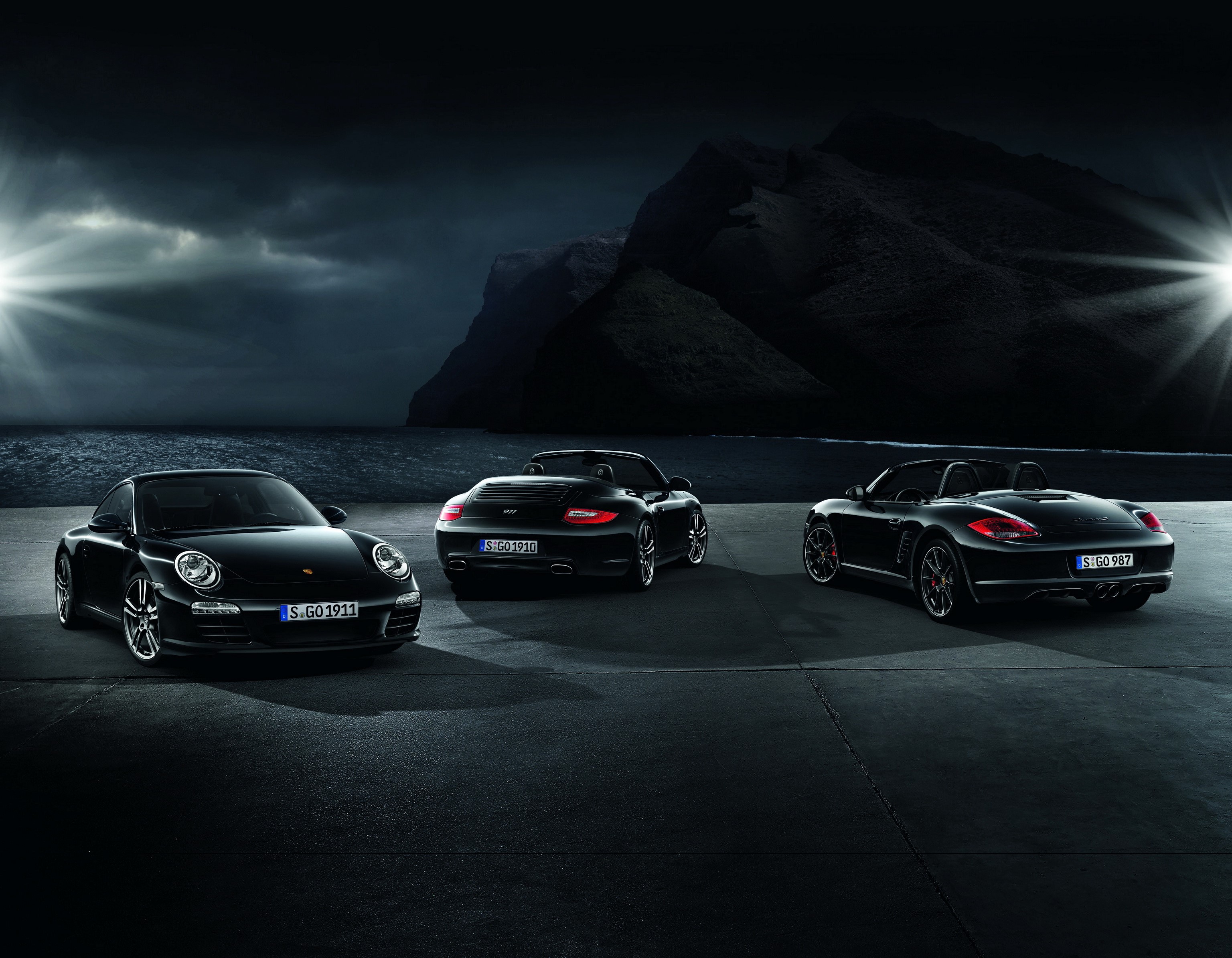 Three black Porsche cars parked by the sea at night HD Wallpaper