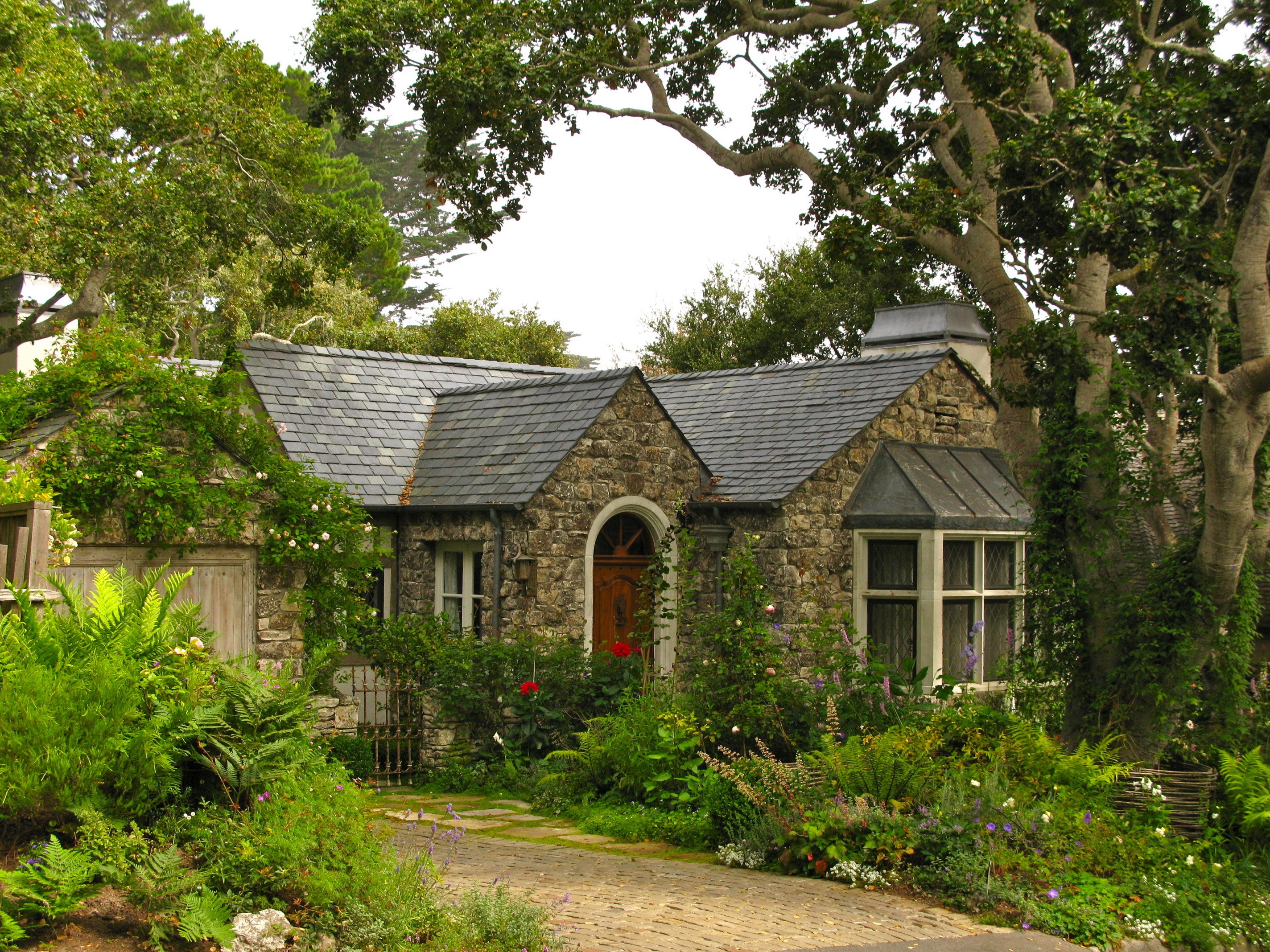 Stone cottage with lush garden and trees HD Wallpaper