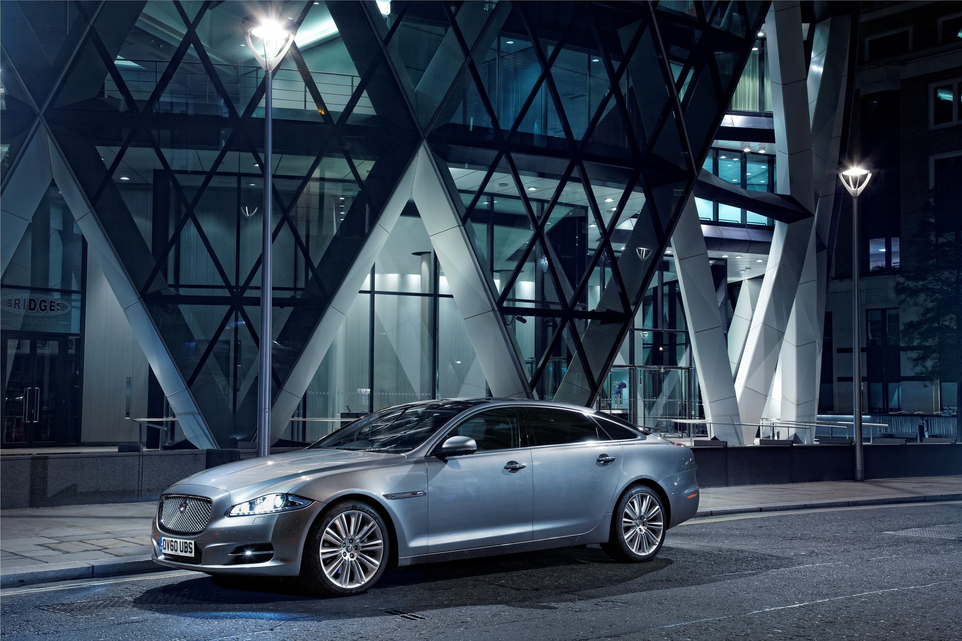 Silver Jaguar XJ LWB parked in front of a modern building at night HD Wallpaper