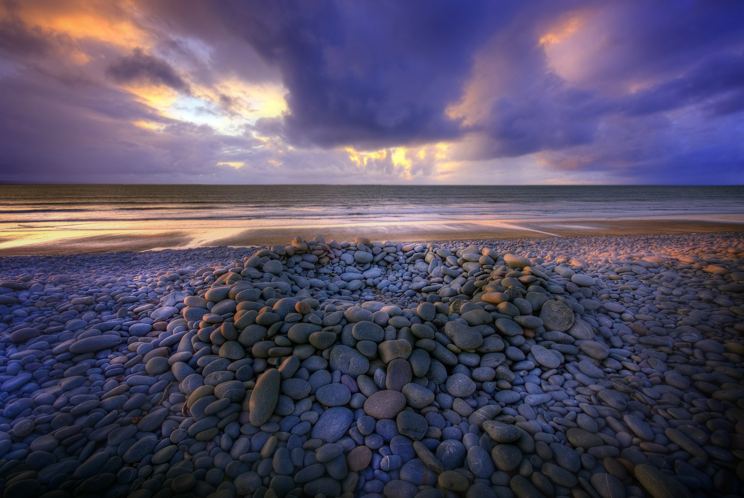 Pebble beach with dramatic sunset clouds over the sea HD Wallpaper