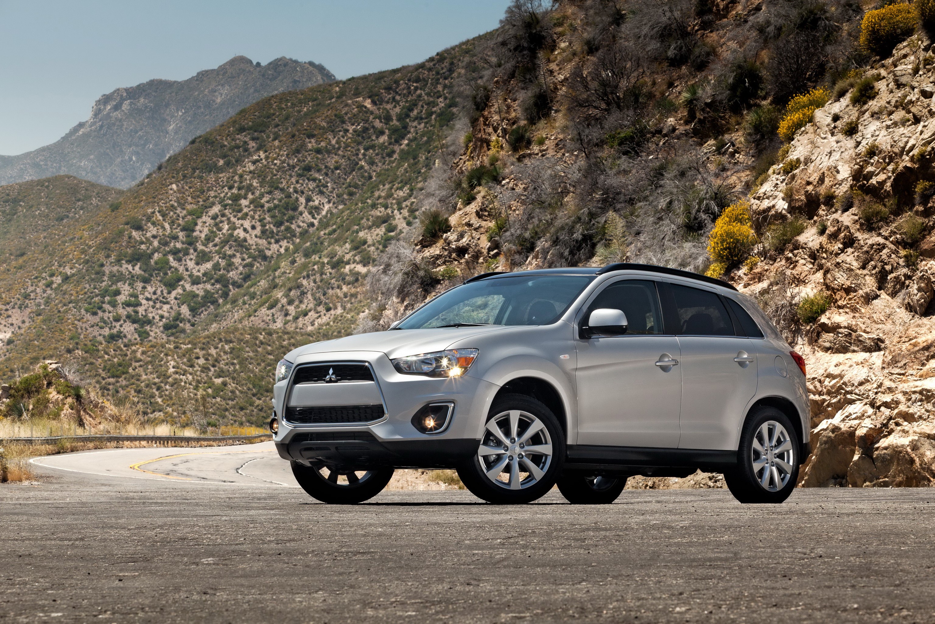 Silver 2013 Mitsubishi Outlander Sport SE on a mountain road HD Wallpaper
