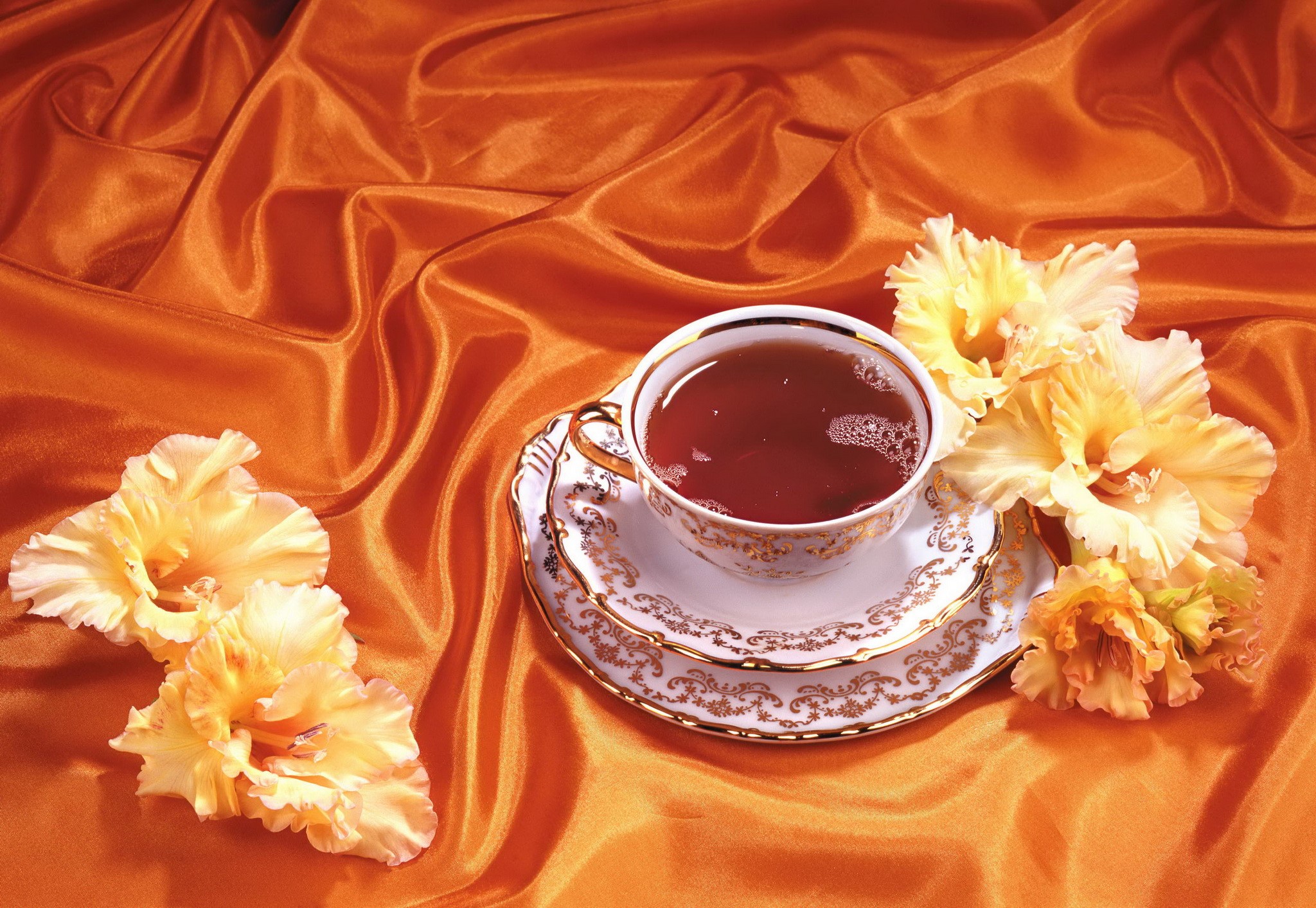Tea cup and saucer with gladiolus flowers on orange silk HD Wallpaper