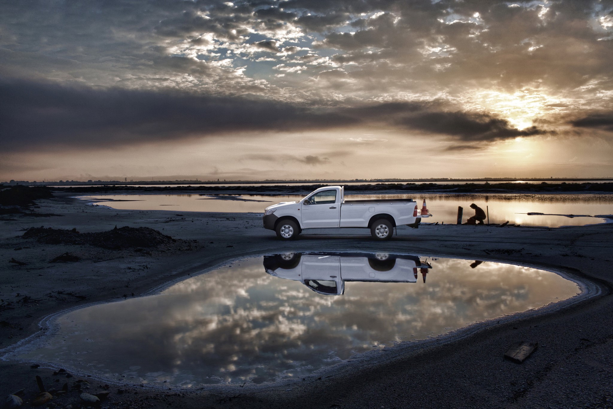 White Toyota Hilux parked by a salt flat at sunset HD Wallpaper