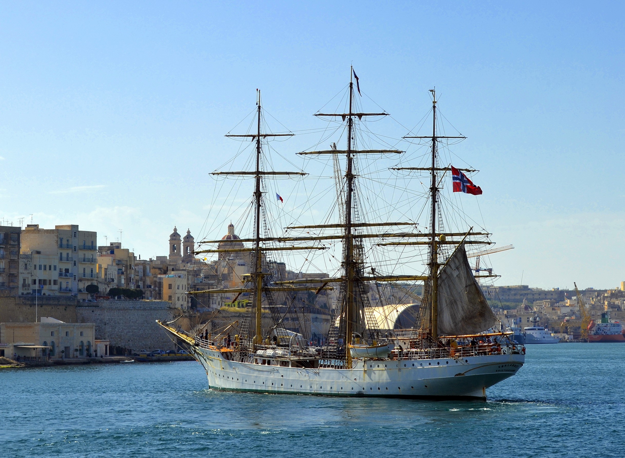 Tall ship sailing in a harbor with city in background HD Wallpaper