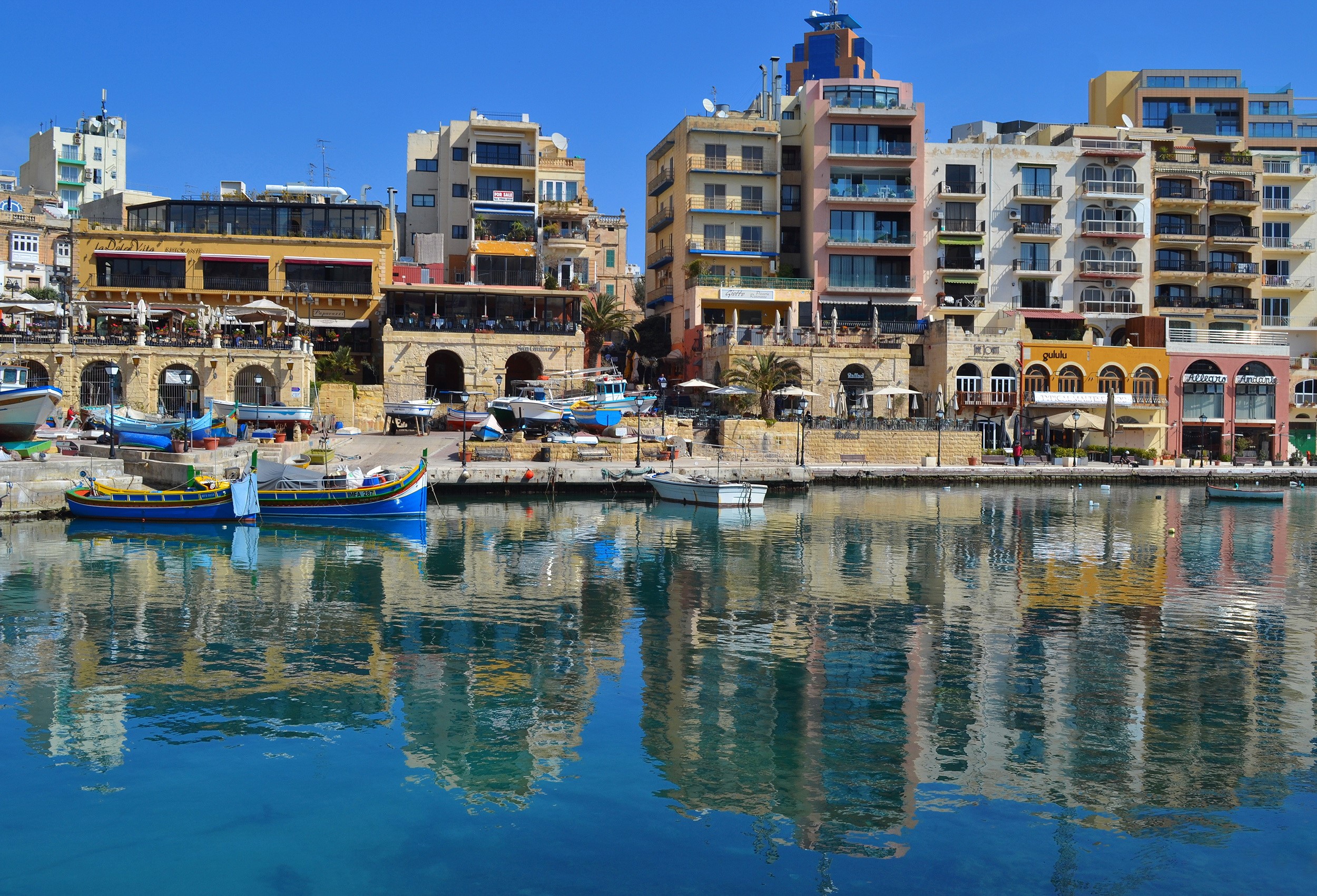 Boats docked in a harbor with colorful buildings in St. Julian's, Malta HD Wallpaper