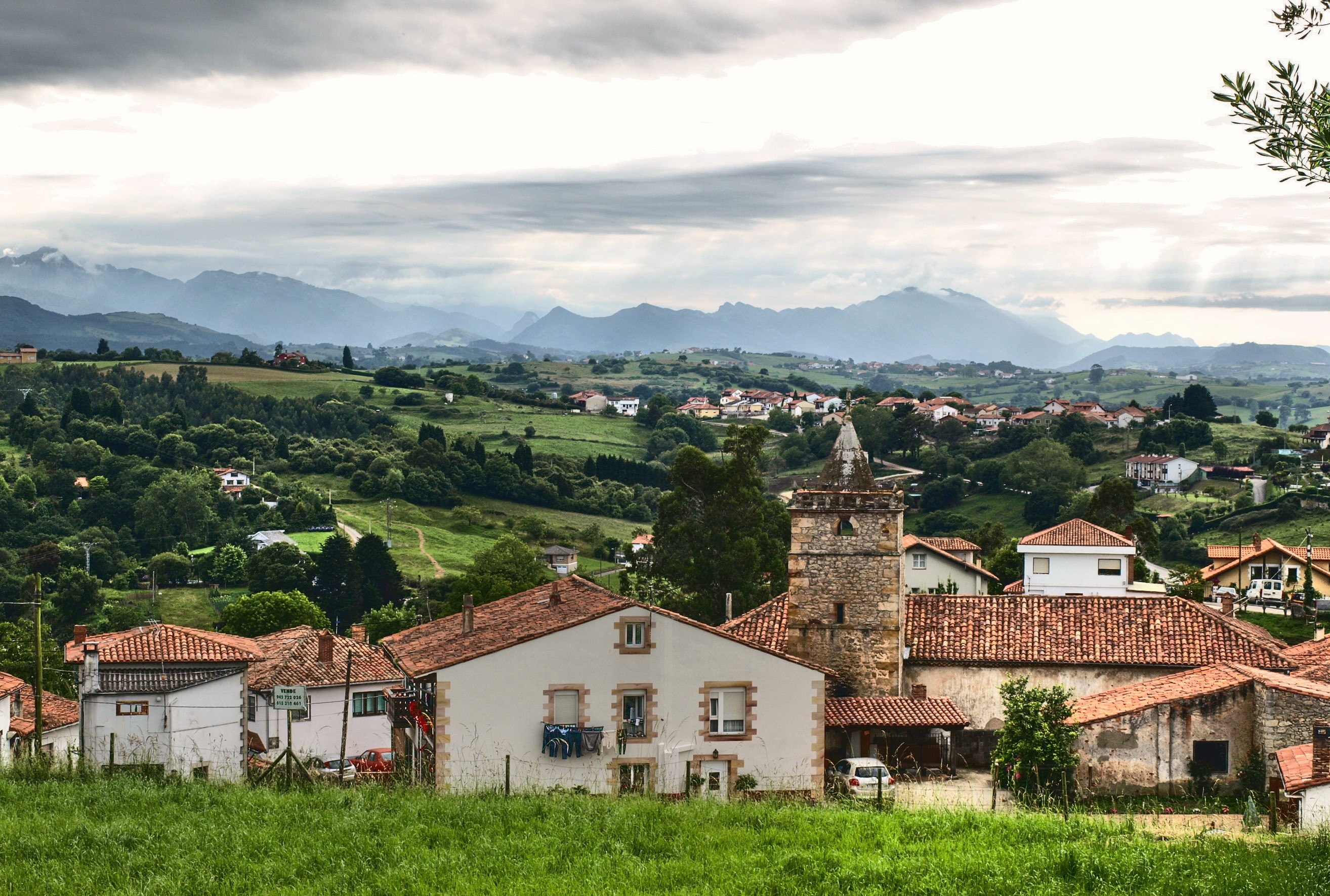 Village with church tower and mountains in Comillas, Spain HD Wallpaper
