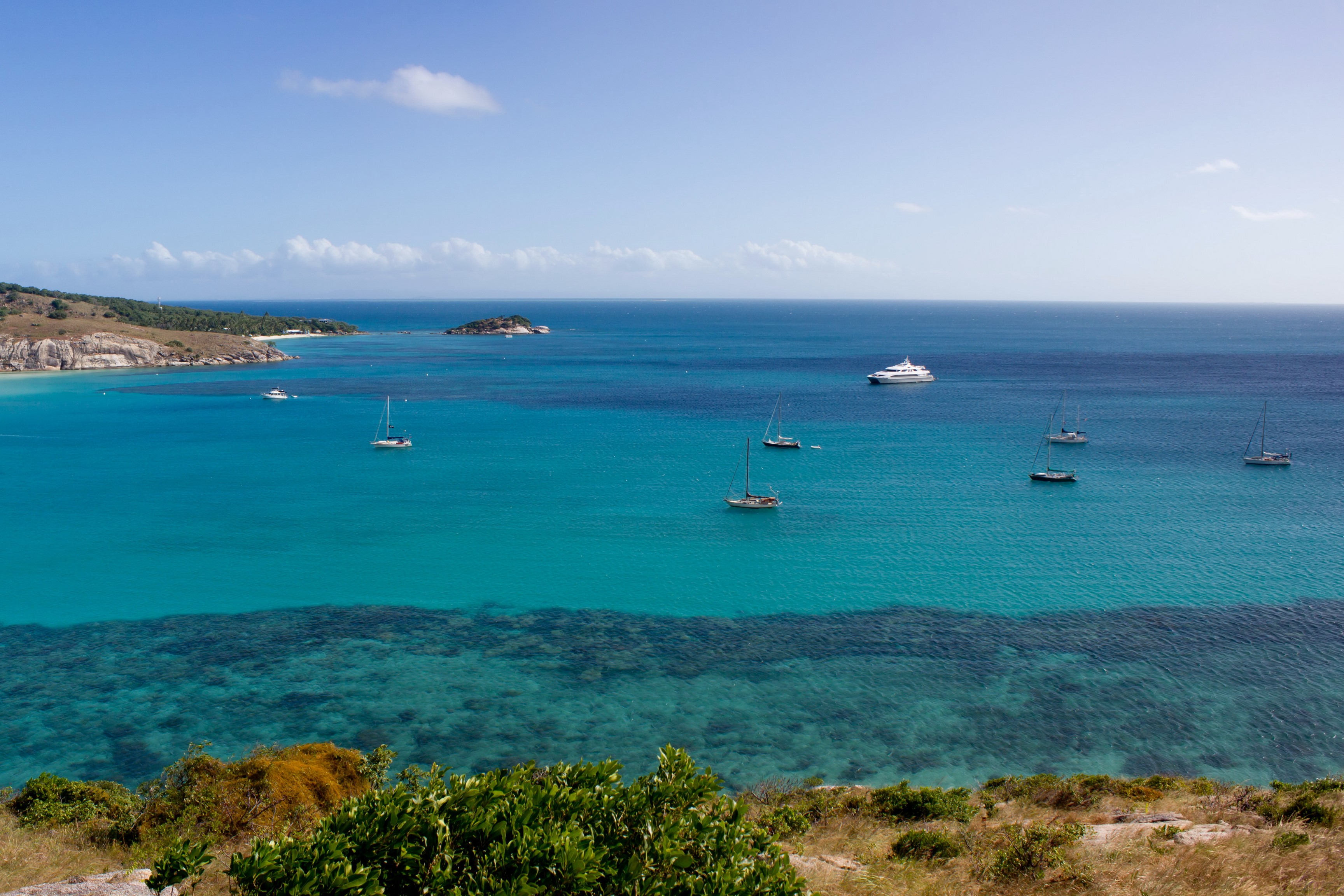 Sailboats and yachts in a turquoise bay near a tropical island HD Wallpaper