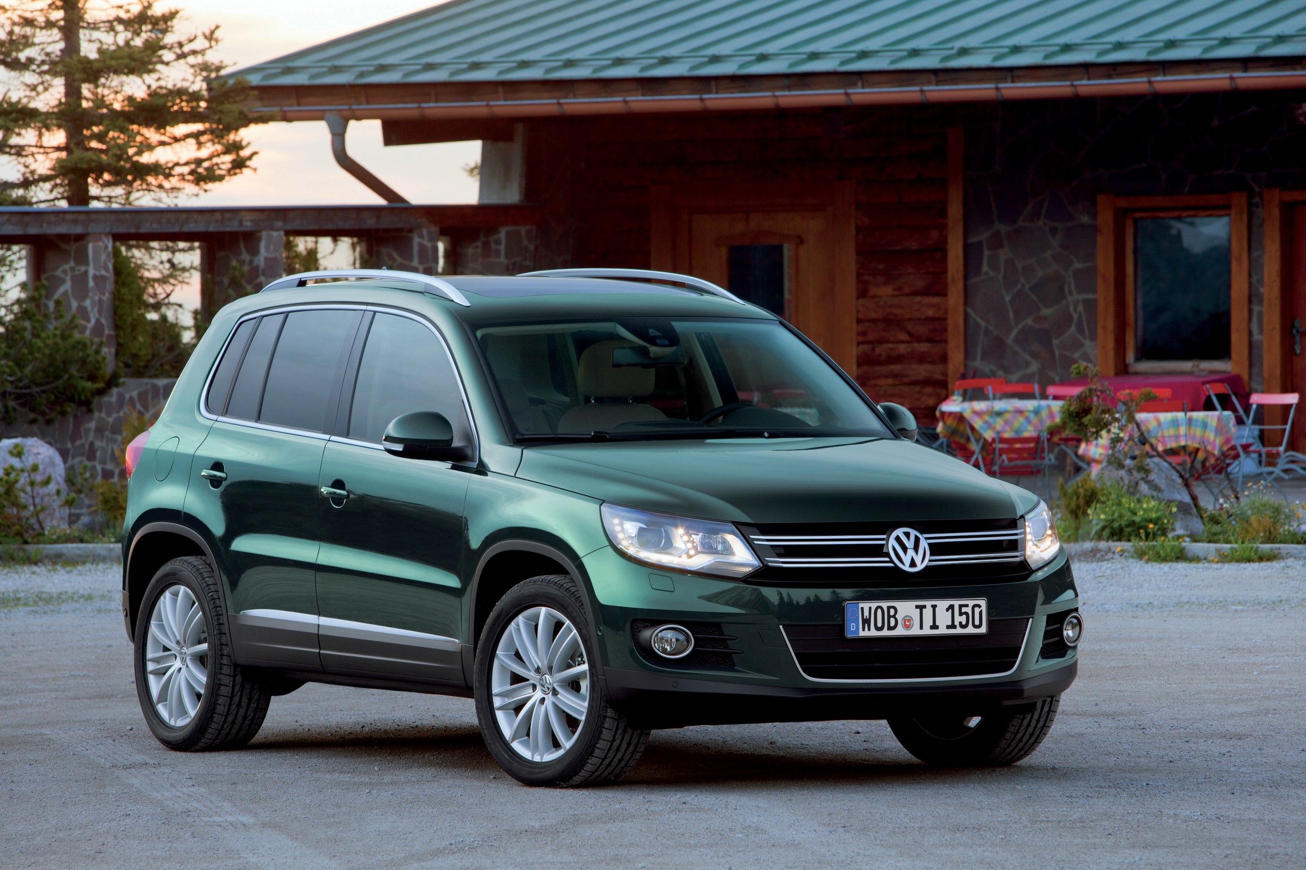 Green 2011 Volkswagen Tiguan parked in front of a lodge HD Wallpaper