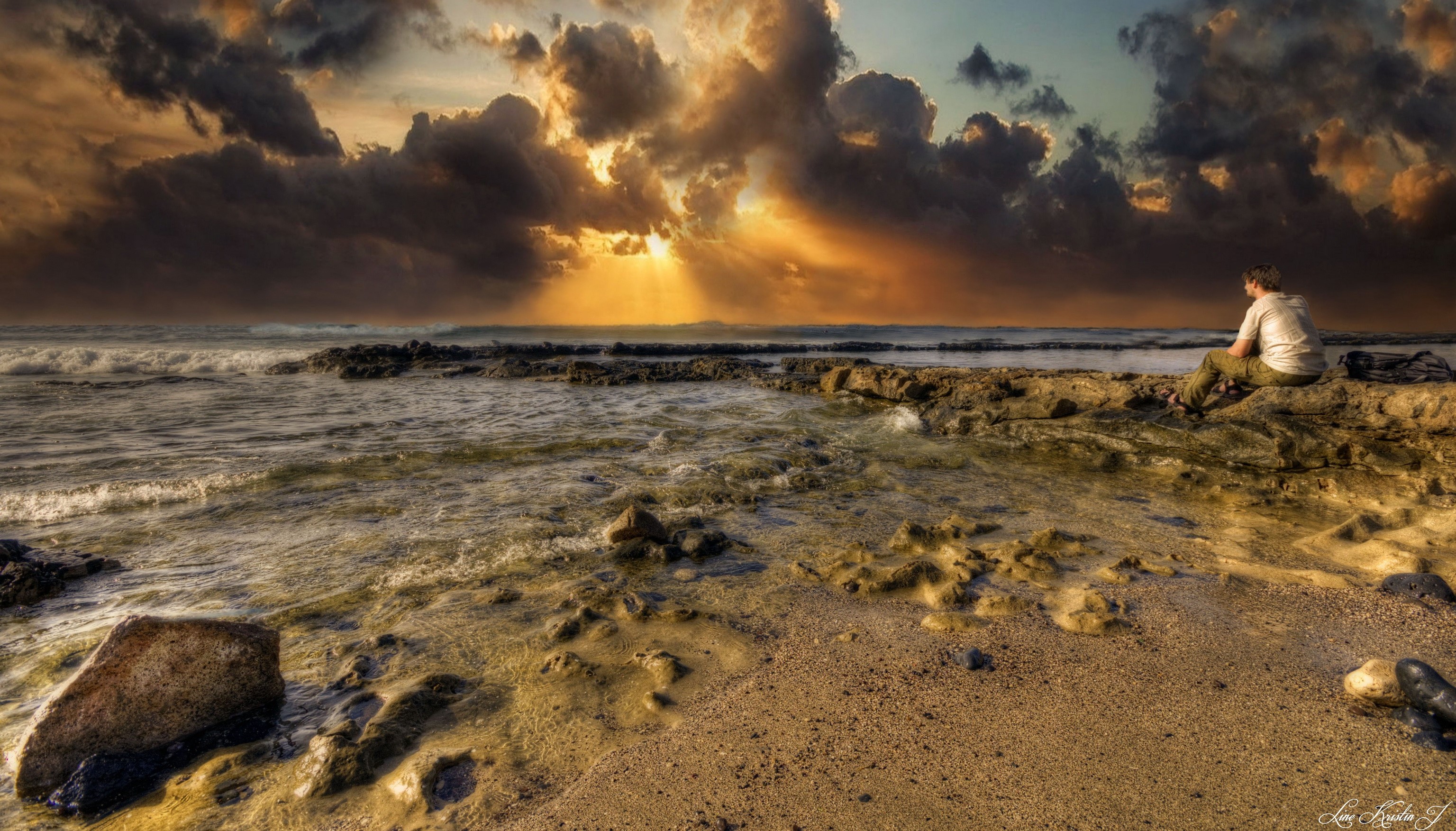 Man sitting on rocks by the sea in Tenerife, Spain HD Wallpaper
