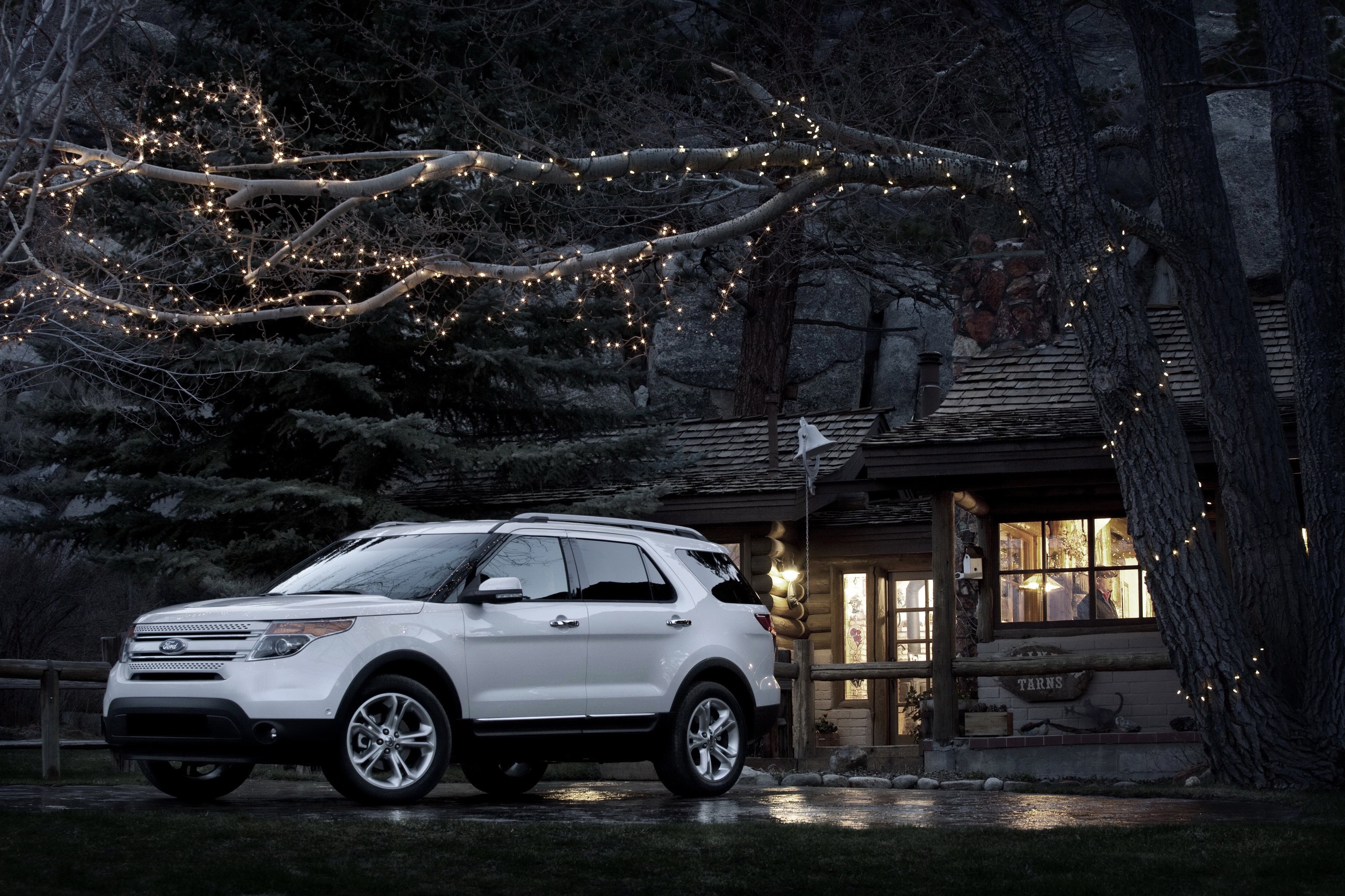 White Ford Explorer parked near a cabin with fairy lights HD Wallpaper