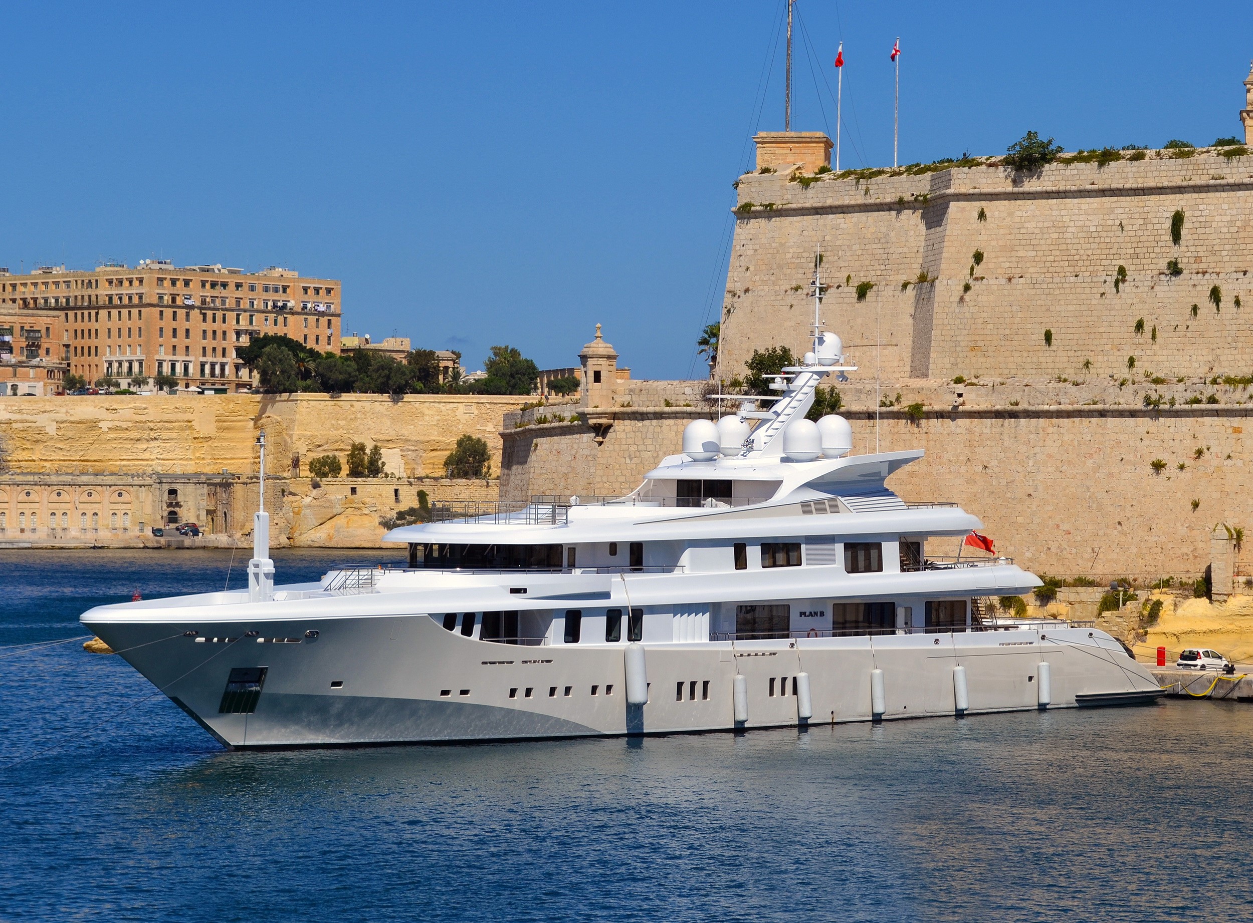 Superyacht Plan B docked near historic fortifications HD Wallpaper