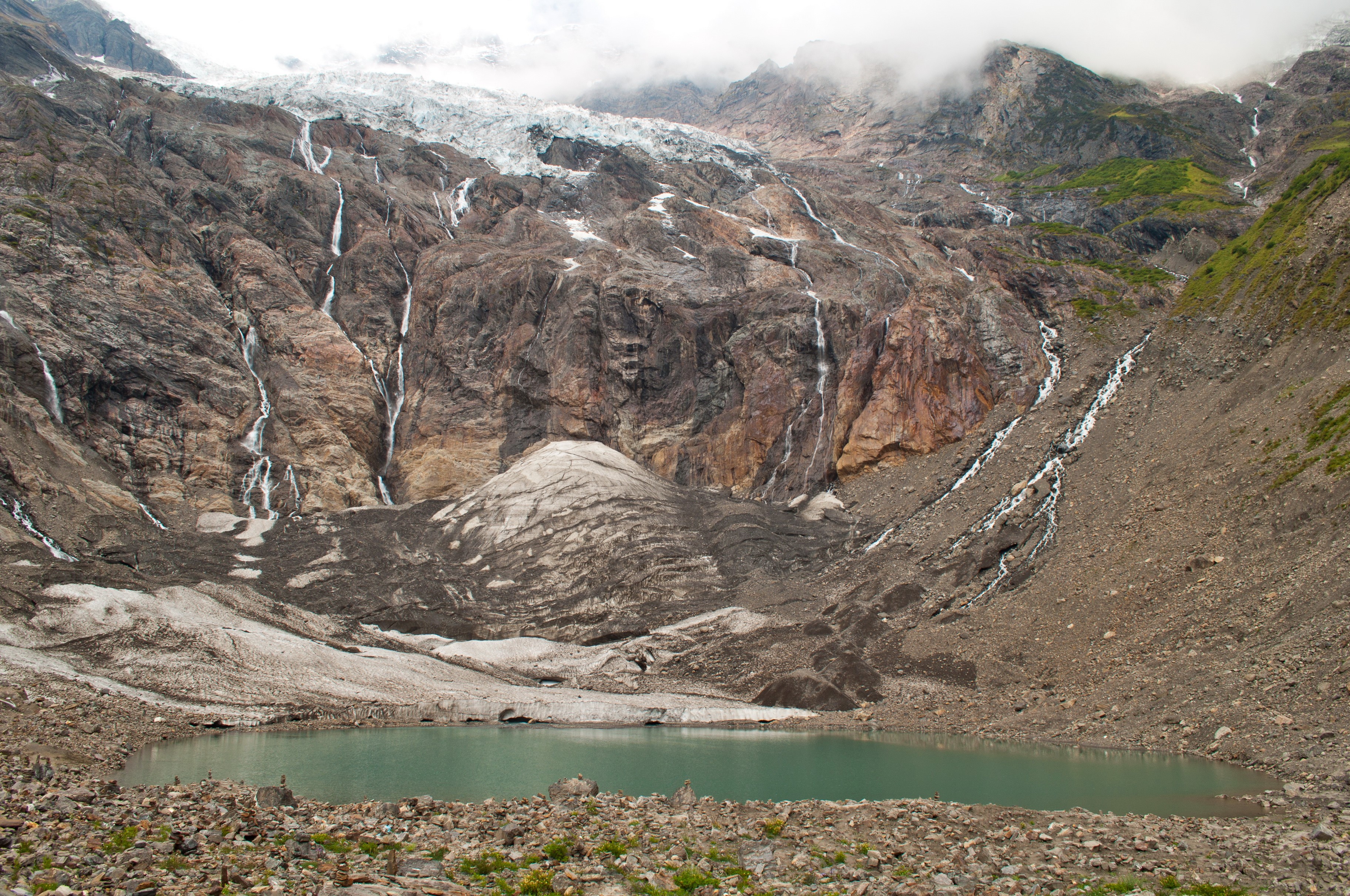 Glacier lake with waterfalls cascading down a rocky mountain HD Wallpaper