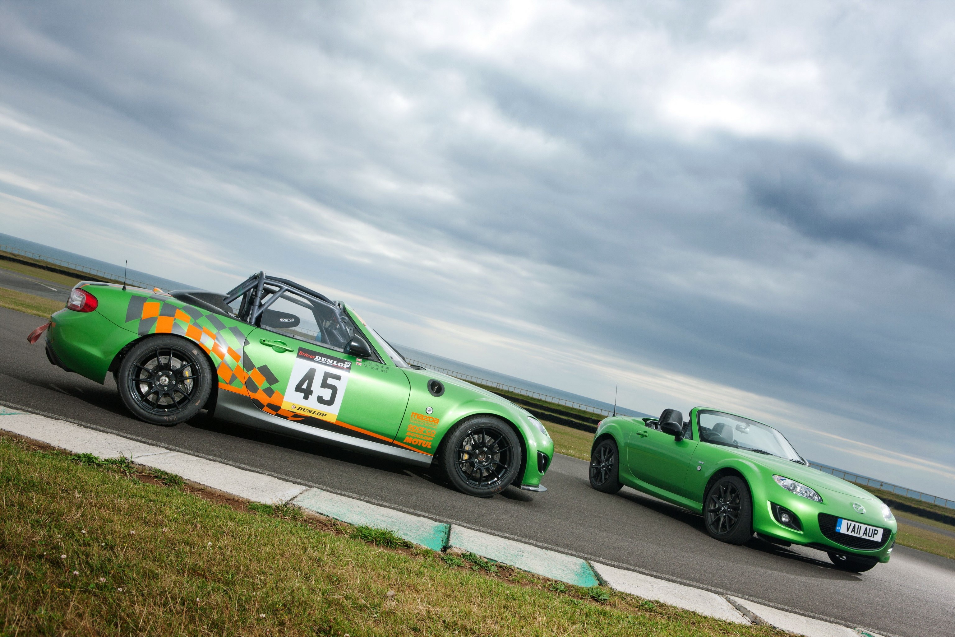 Two green Mazda MX-5 sports cars on a race track HD Wallpaper