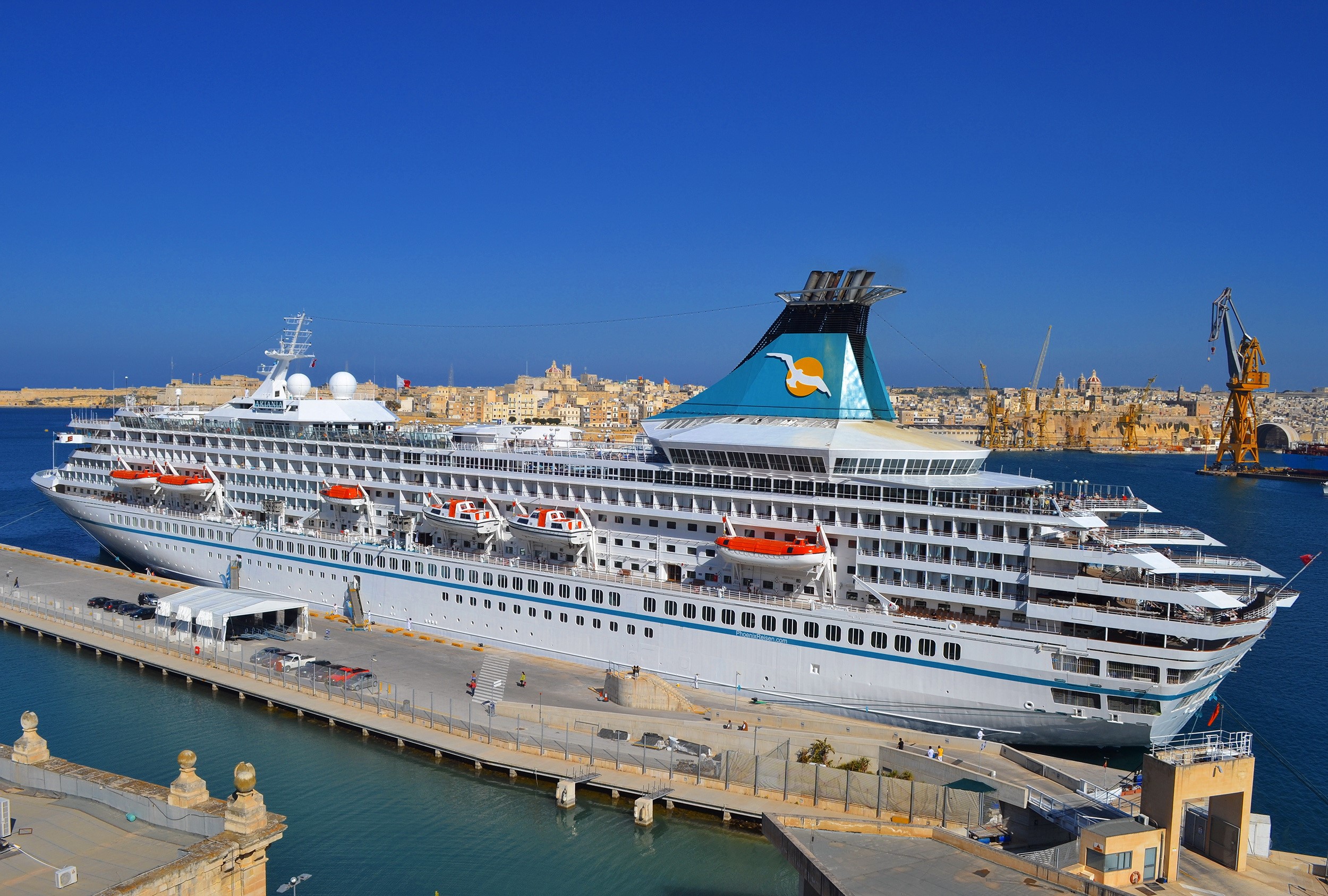Artania cruise liner docked in a harbor with city in background HD Wallpaper
